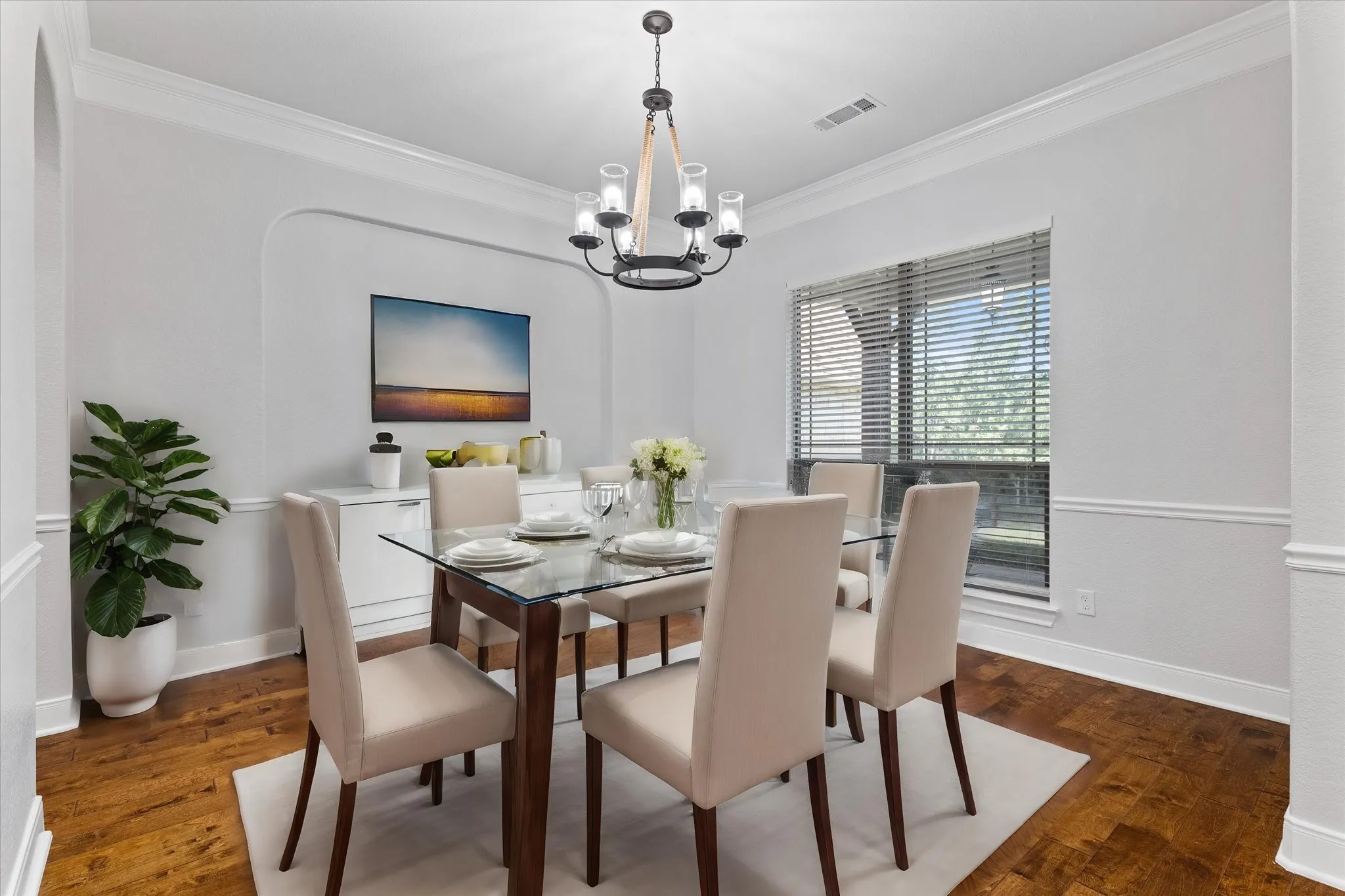 Hardwood flooring, crown molding, chair rail molding, arched entryway, and a chandelier with glass shades