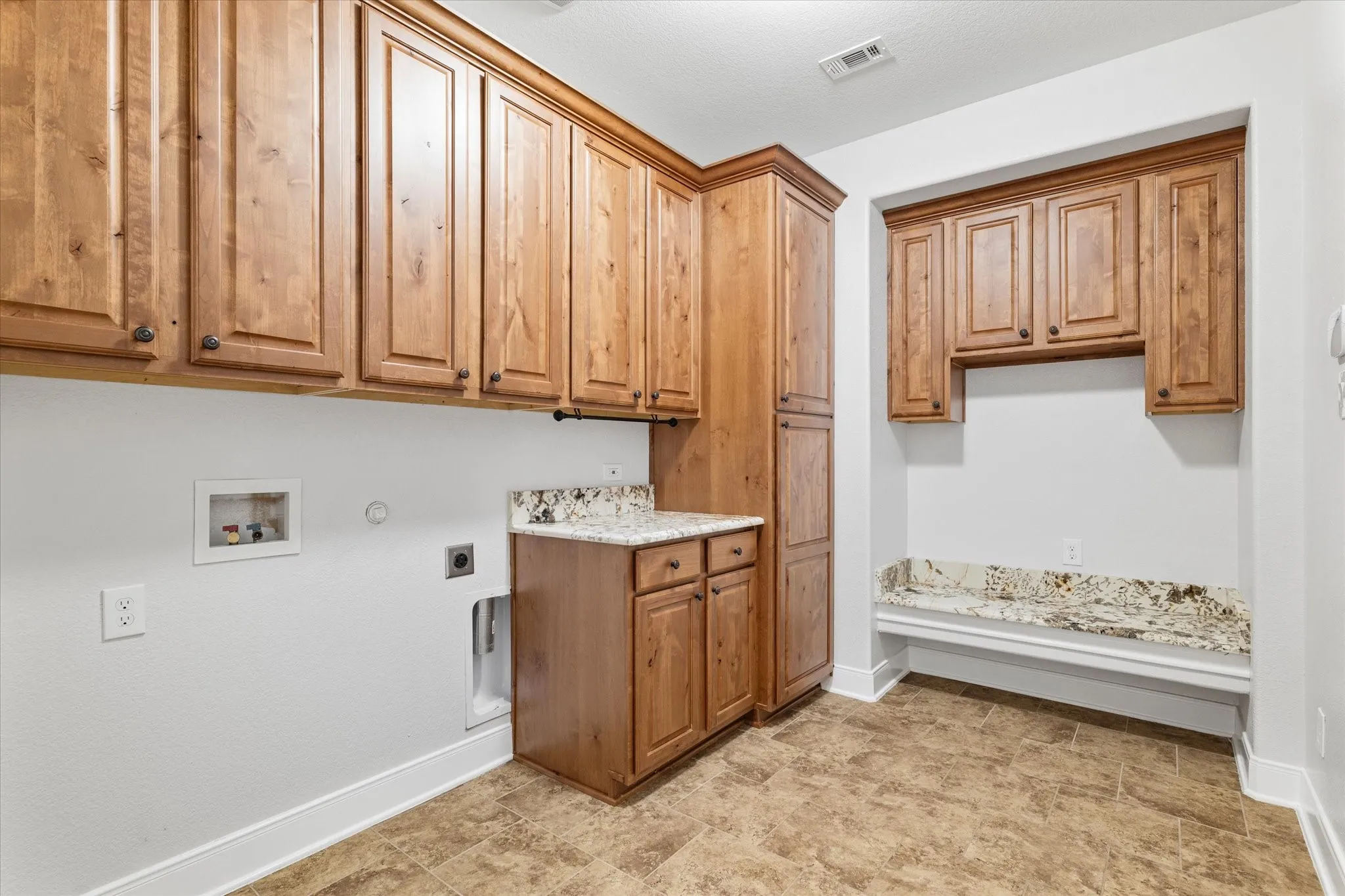 Built-in cabinetry with wood-finish doors, granite-style countertops, and tiled flooring