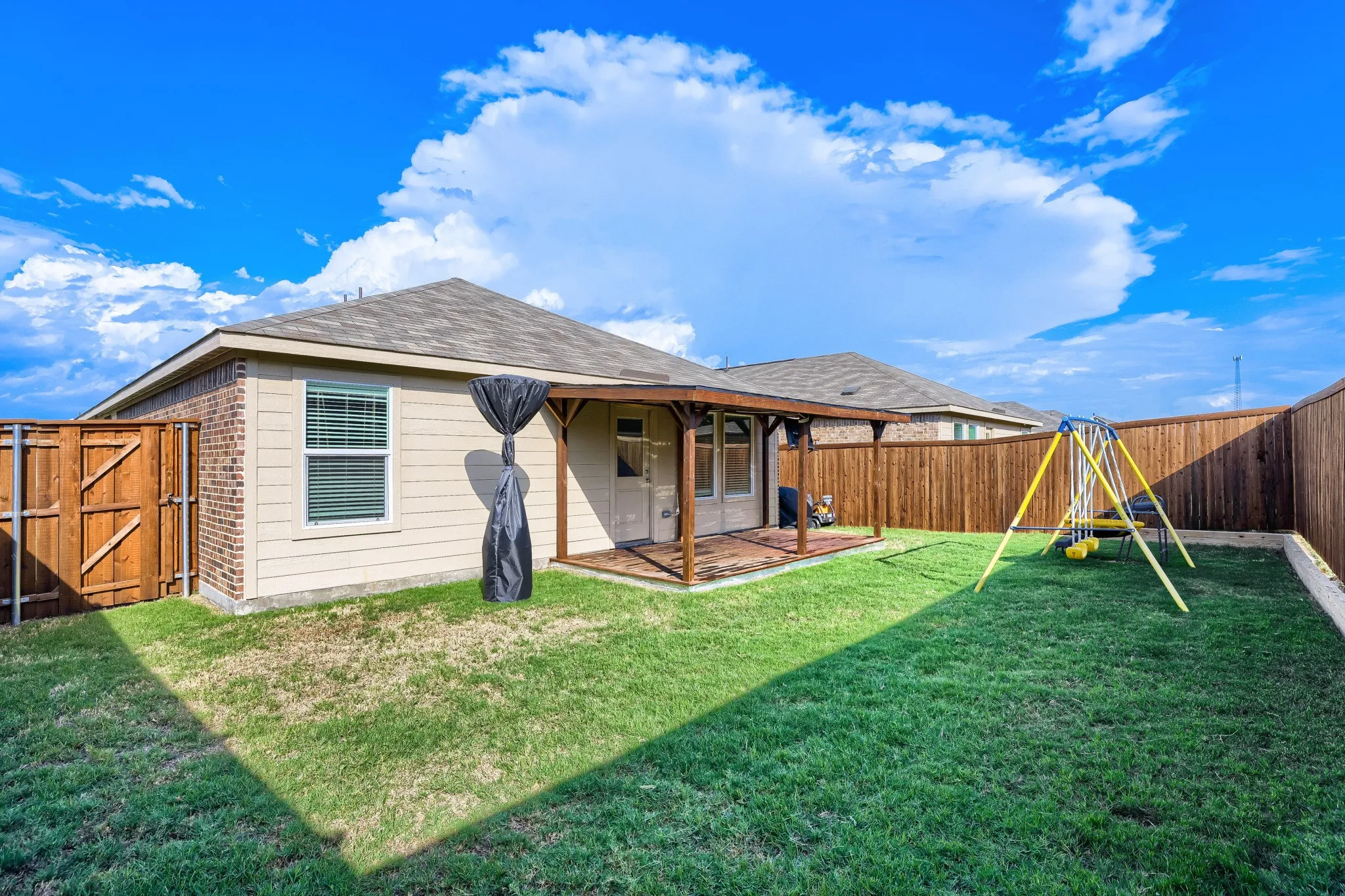 Expansive fenced backyard featuring a covered patio with wood-finish decking and a wooden privacy fence