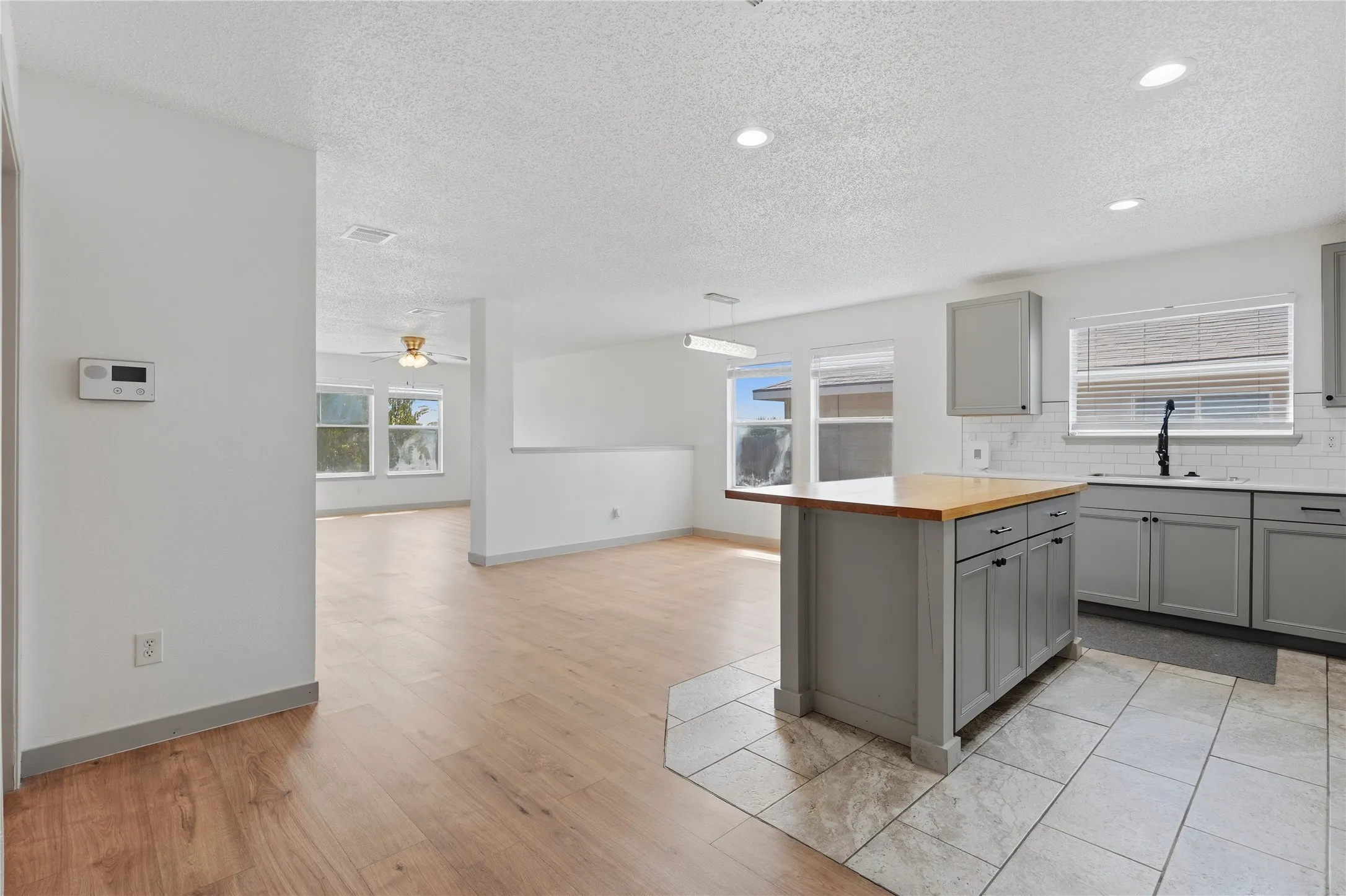 Kitchen featuring a central island with a wood-finish countertop, gray cabinetry, and a white subway tile backsplash