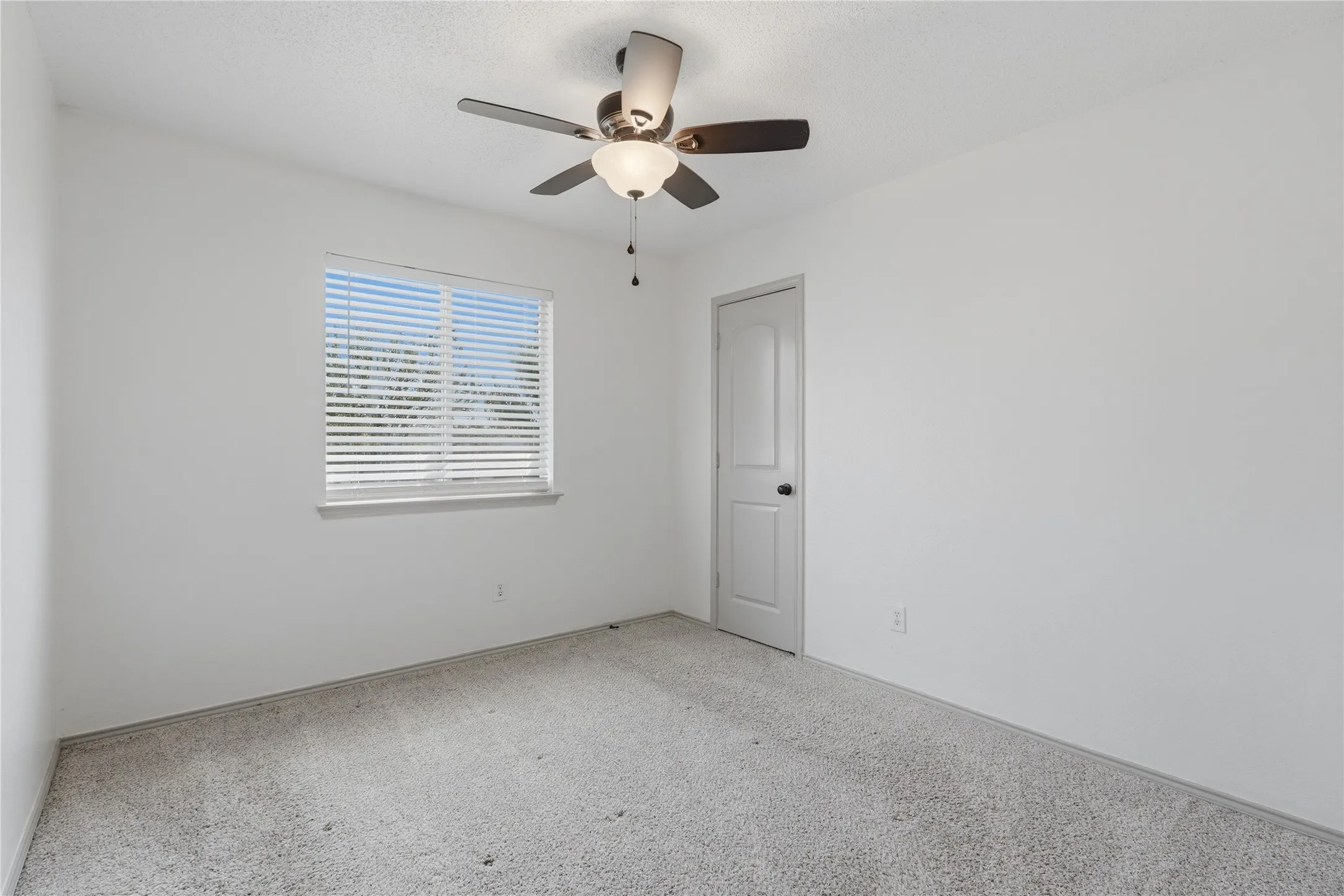 Recessed window with horizontal blinds, neutral wall paint, ceiling fan with integrated lighting, textured ceiling, and light-toned carpet