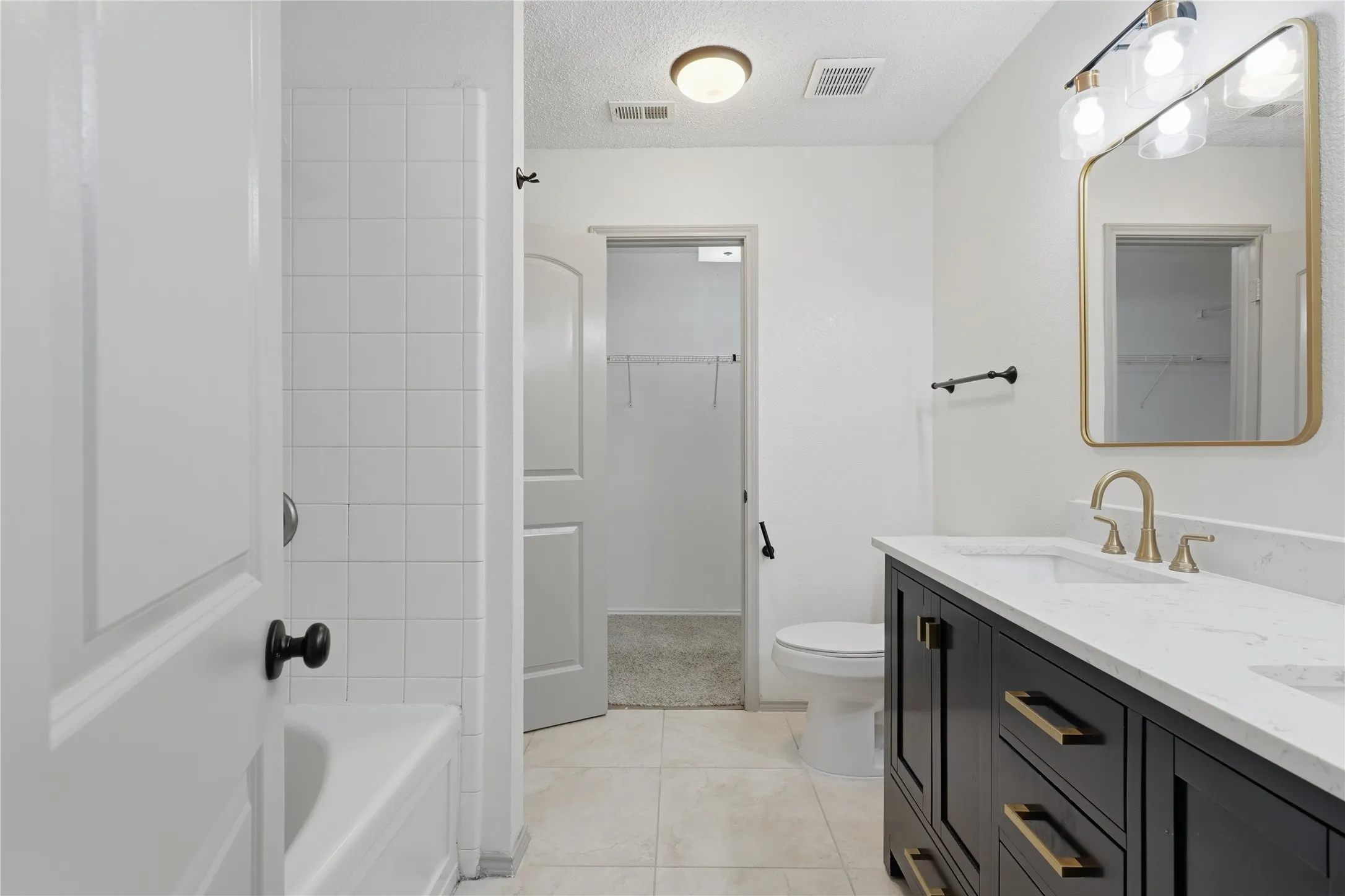 Dual vanity with white countertop, dark wood-finish cabinetry, and gold-toned fixtures