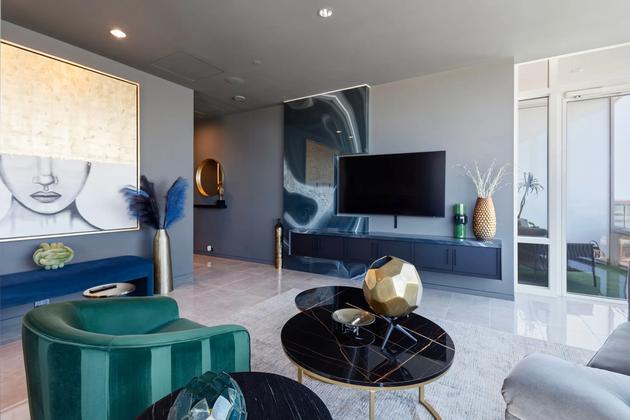 Recessed ceiling lighting, large format tile flooring, a built-in media console, and a wall of windows provide natural illumination