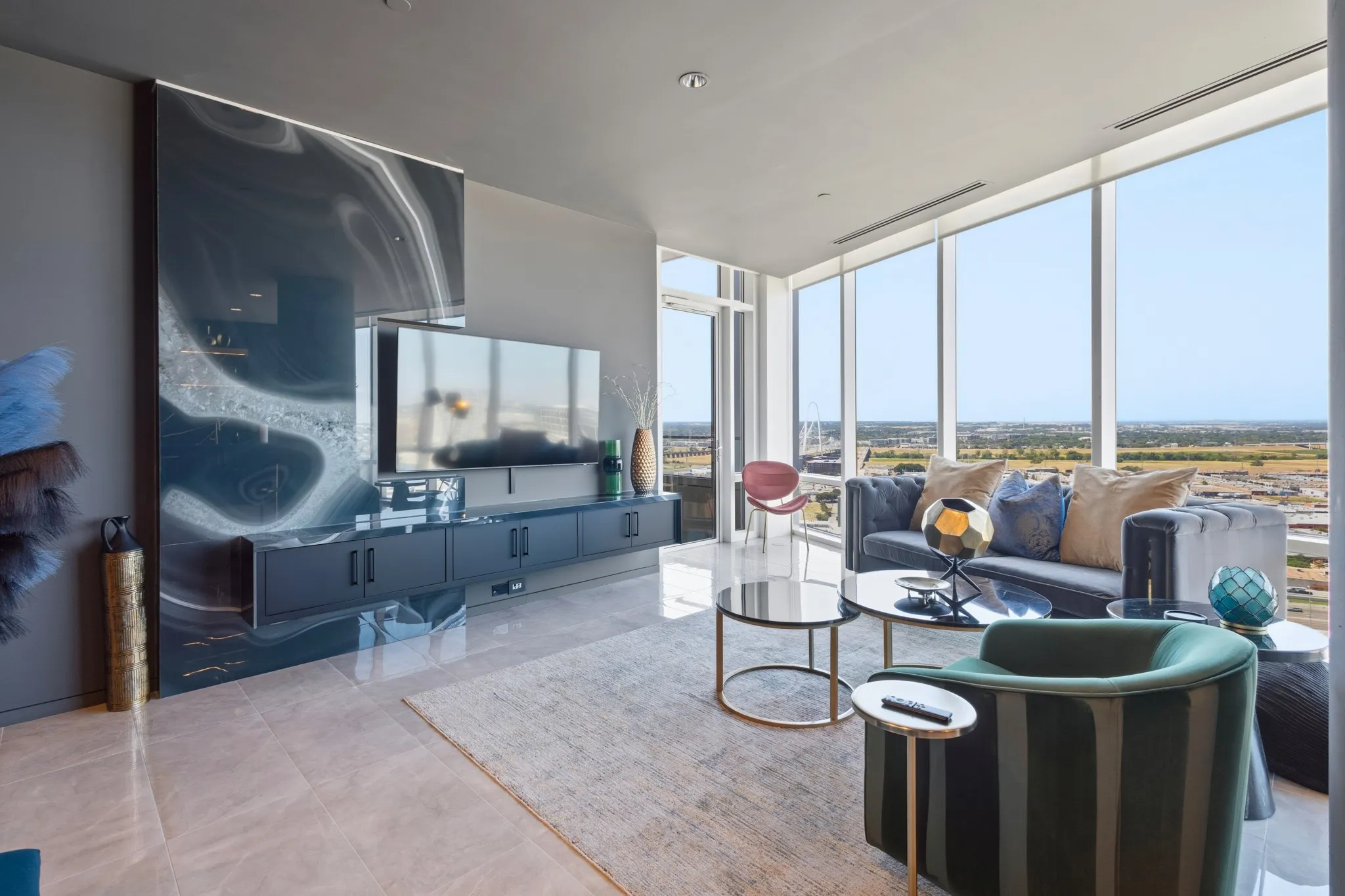 Expansive floor-to-ceiling windows, large format tile flooring, a wall-mounted media console, and a striking accent wall