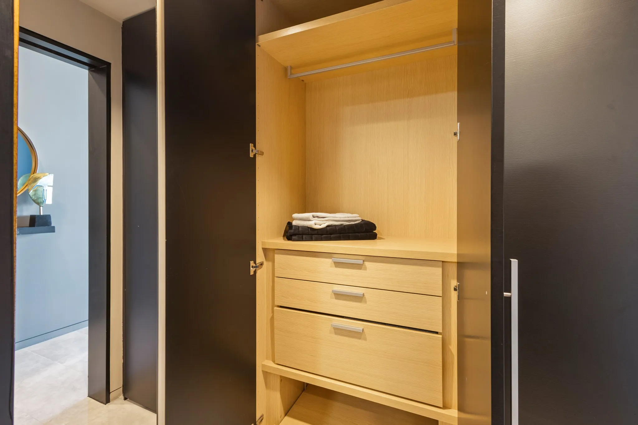 Built-in closet featuring light wood-finish shelving, an upper hanging rod, and two integrated drawers with metal pulls