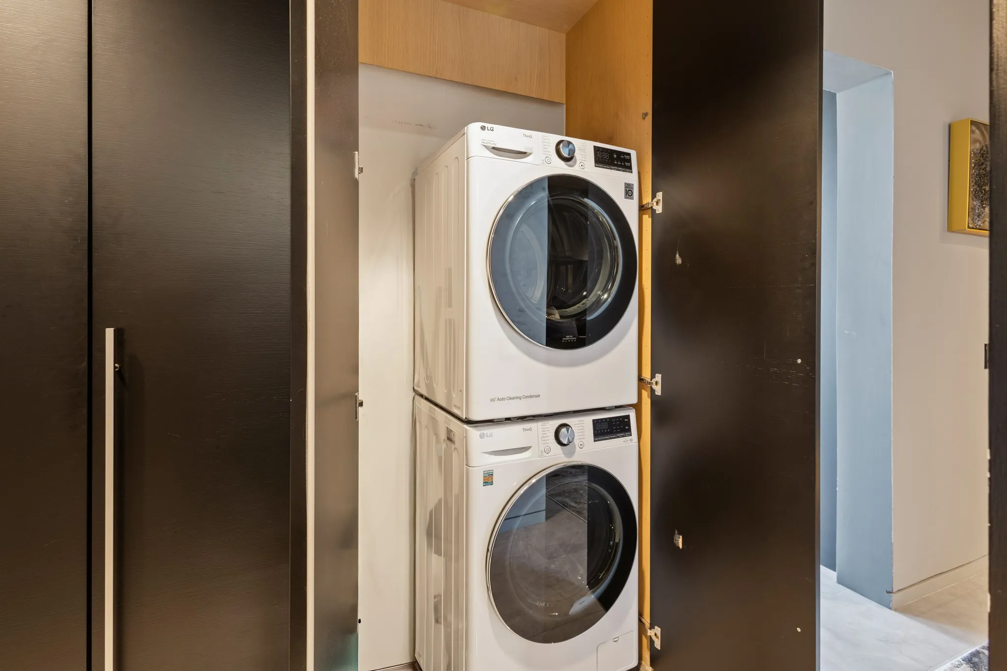 Built-in laundry closet with stacked appliances and dark paneled doors