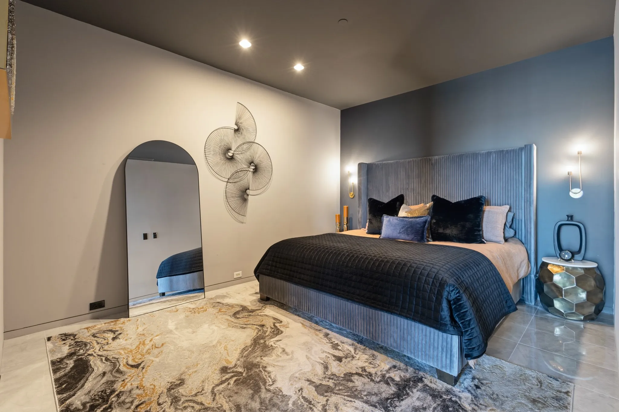 Recessed lighting illuminates a feature wall with sconces, complemented by a textured headboard
