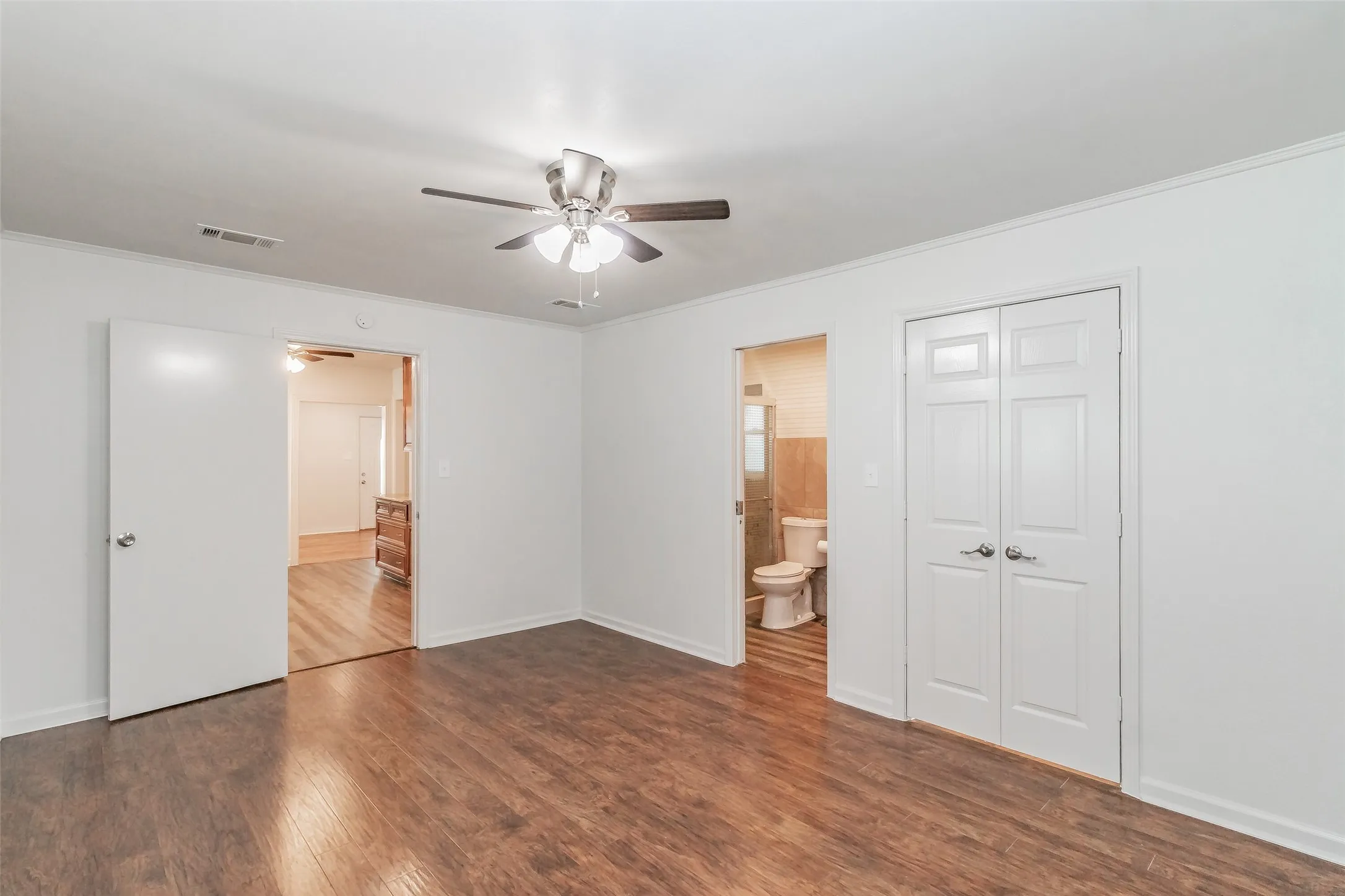 Wood-finish flooring, white walls, and a ceiling fan with integrated lighting