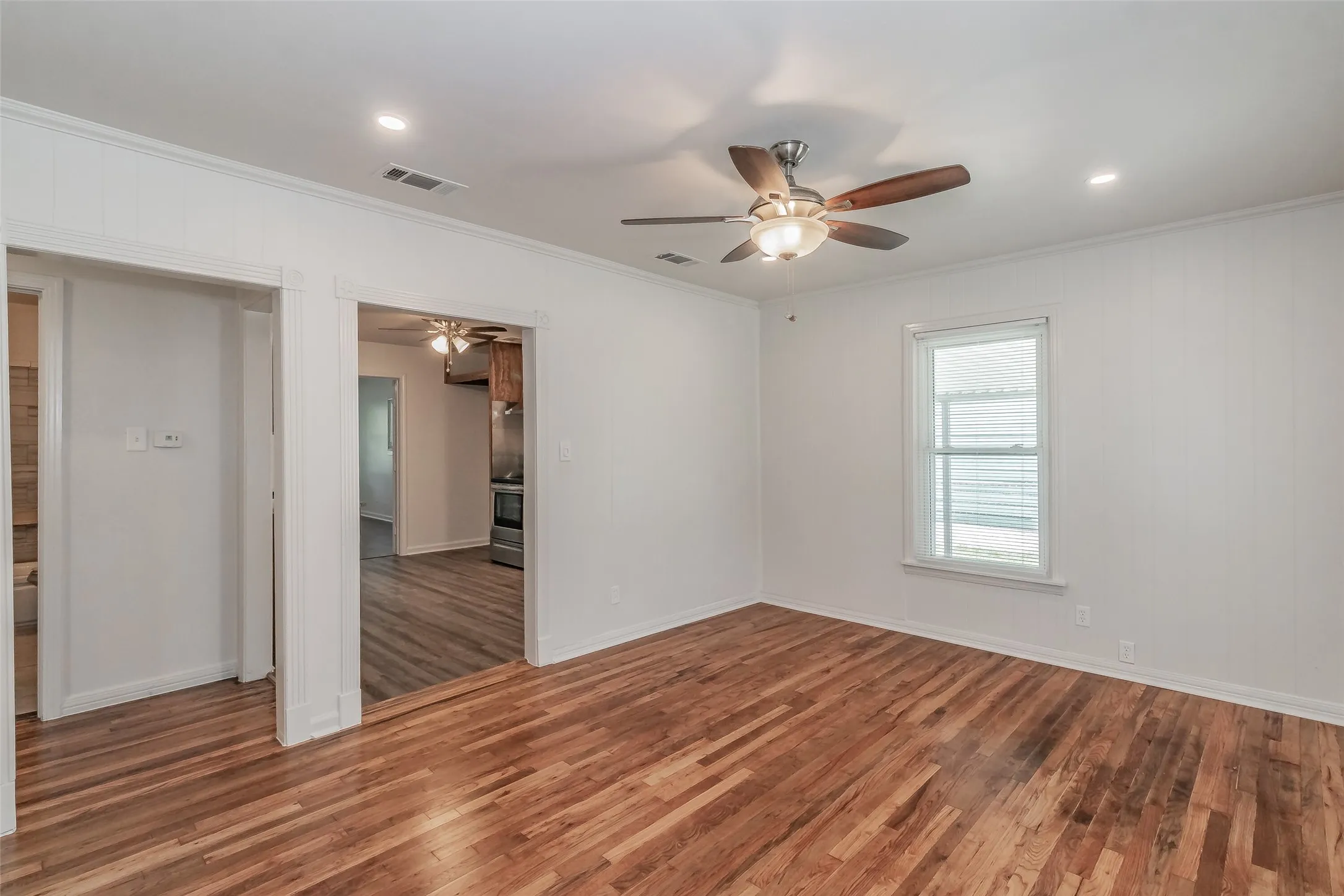 Hardwood flooring, recessed lighting, ceiling fan, white paneled walls, and a window with blinds