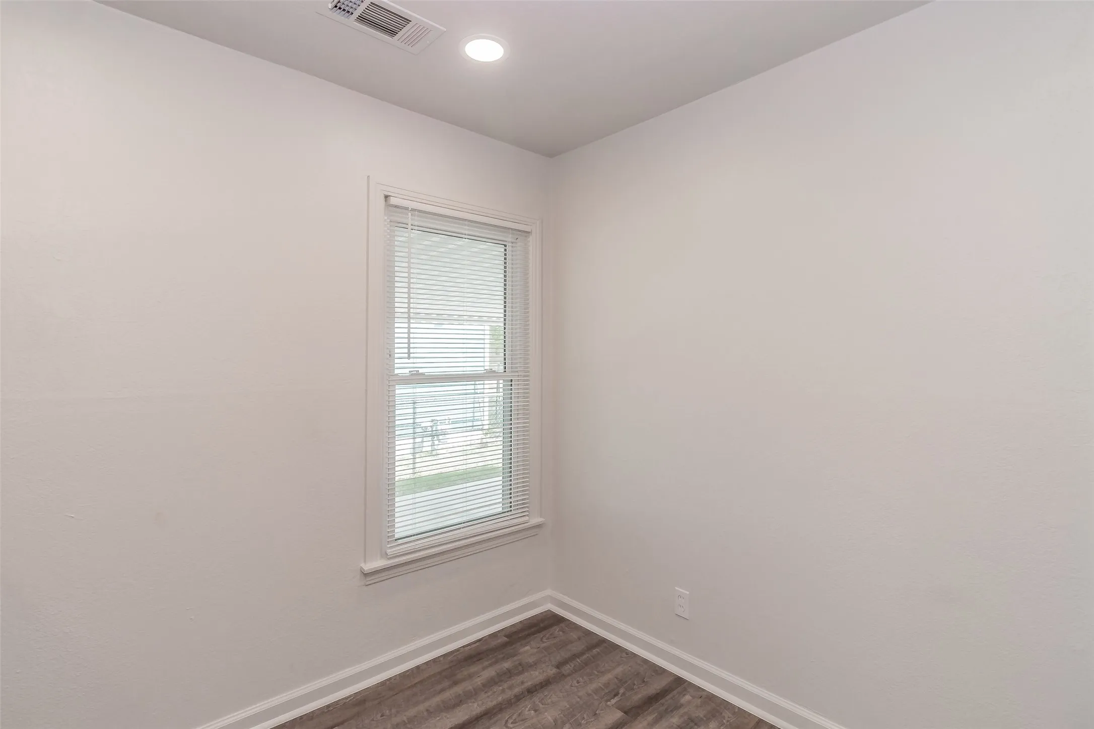 Recessed ceiling lighting, wood-finish flooring, white trim, and a window with blinds