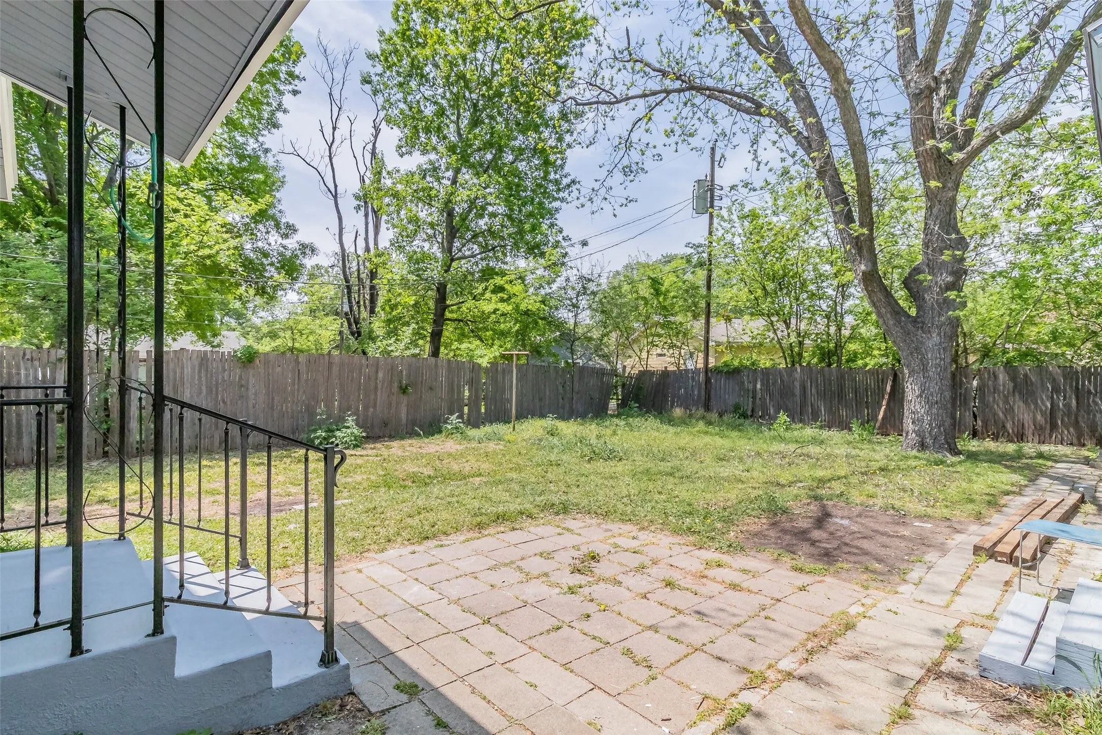 Expansive backyard featuring a mature tree, wood privacy fencing, and a paver patio