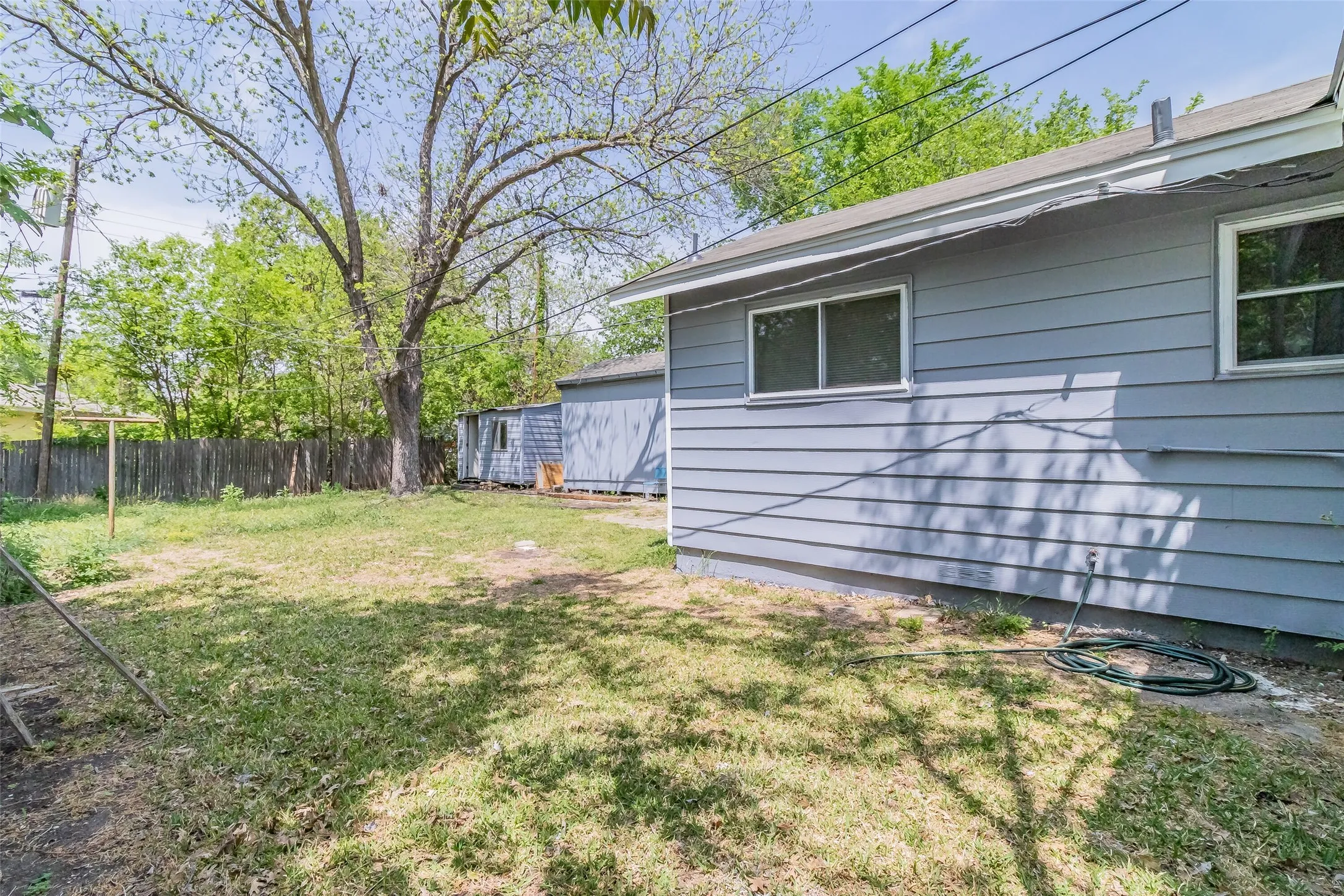 Expansive yard with a large mature tree, a privacy fence, and a detached shed