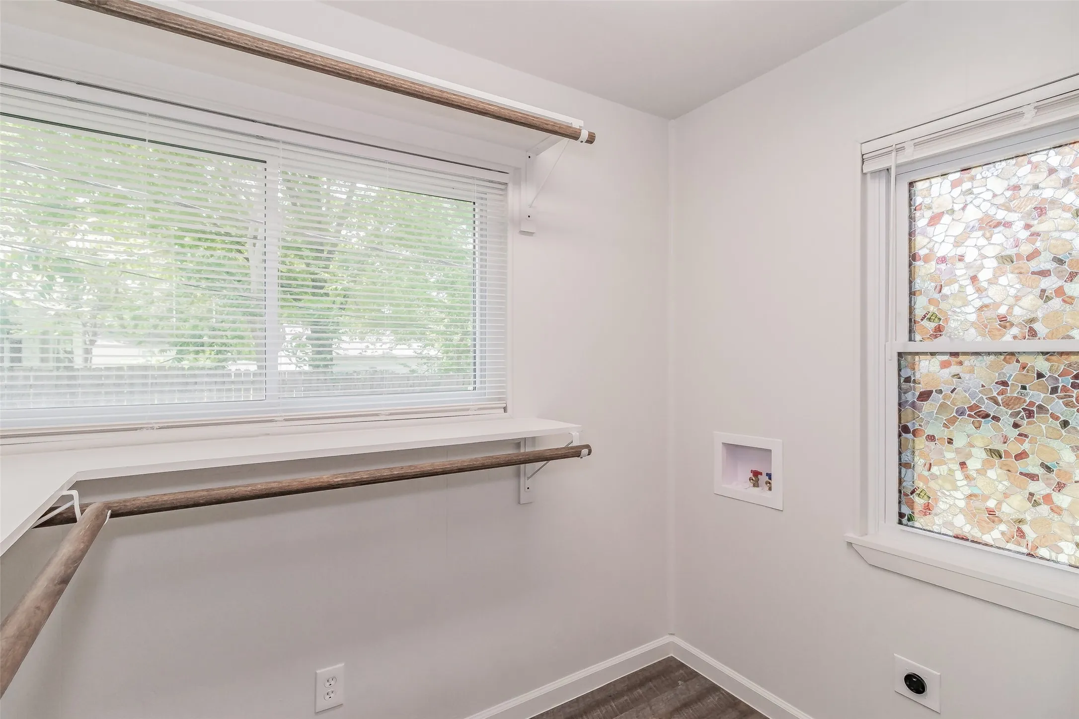 Laundry room featuring wood-finish flooring, two windows, and built-in shelving with a hanging rod