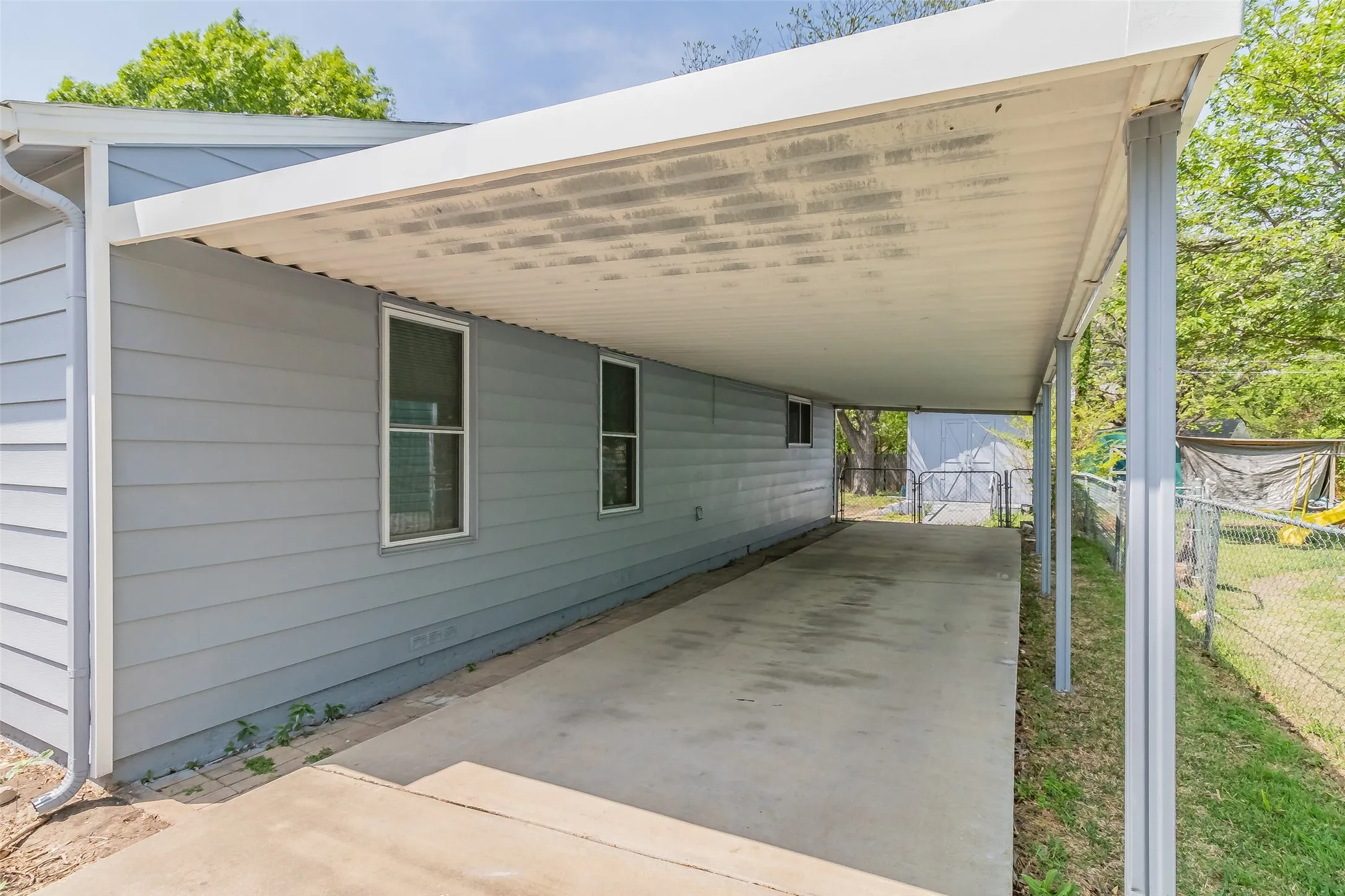 Carport featuring a concrete slab, metal support posts, and an attached gutter system