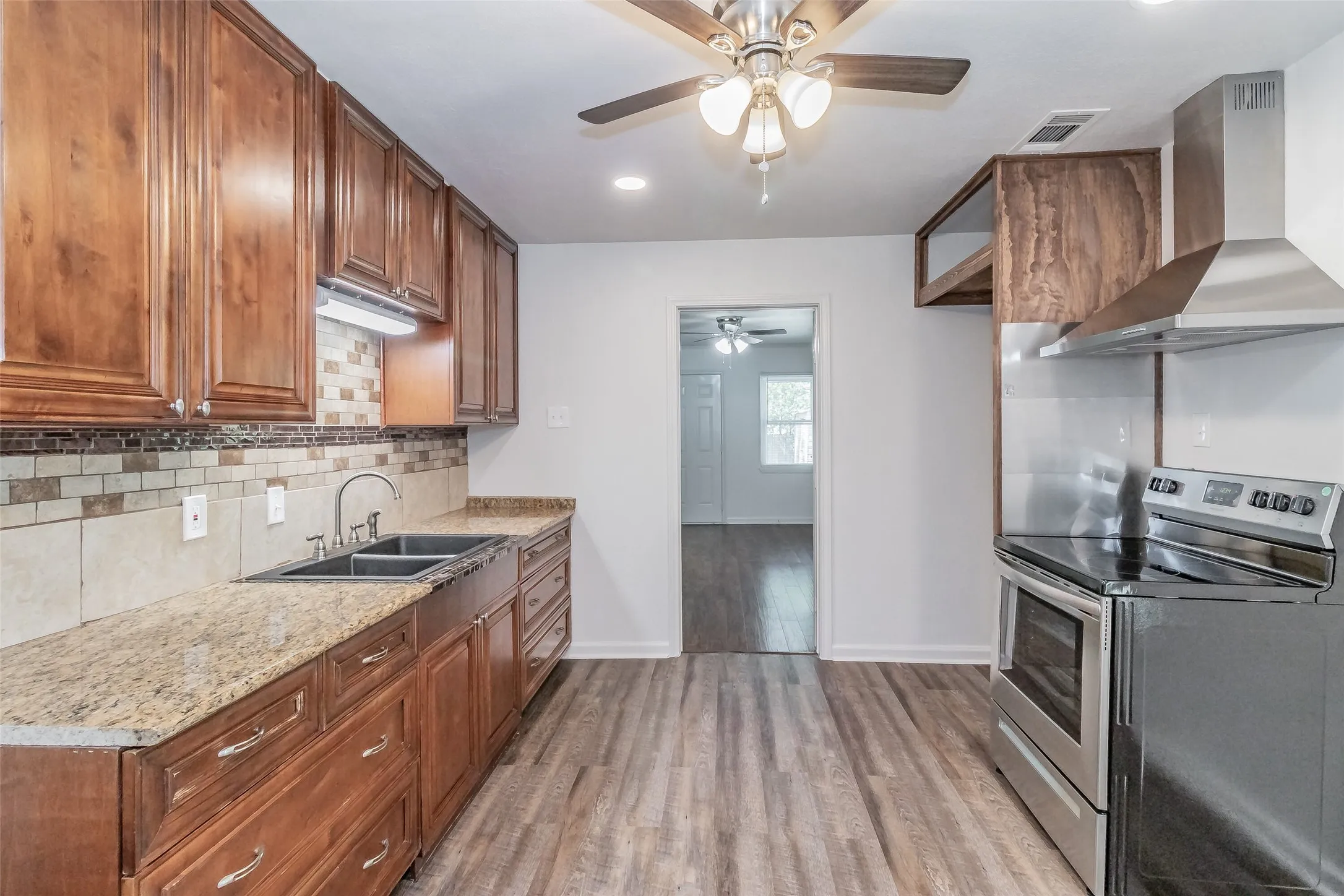 Wood-finish flooring with a neutral wall color, complemented by wood cabinetry and granite-pattern countertops