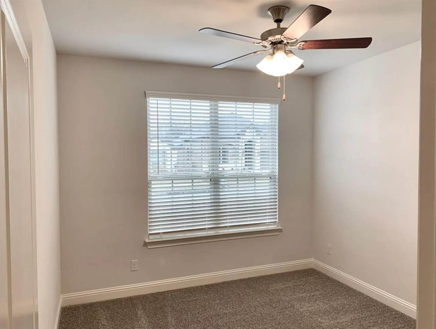Room featuring a ceiling fan with integrated lighting, a window with horizontal blinds, and neutral-toned carpet
