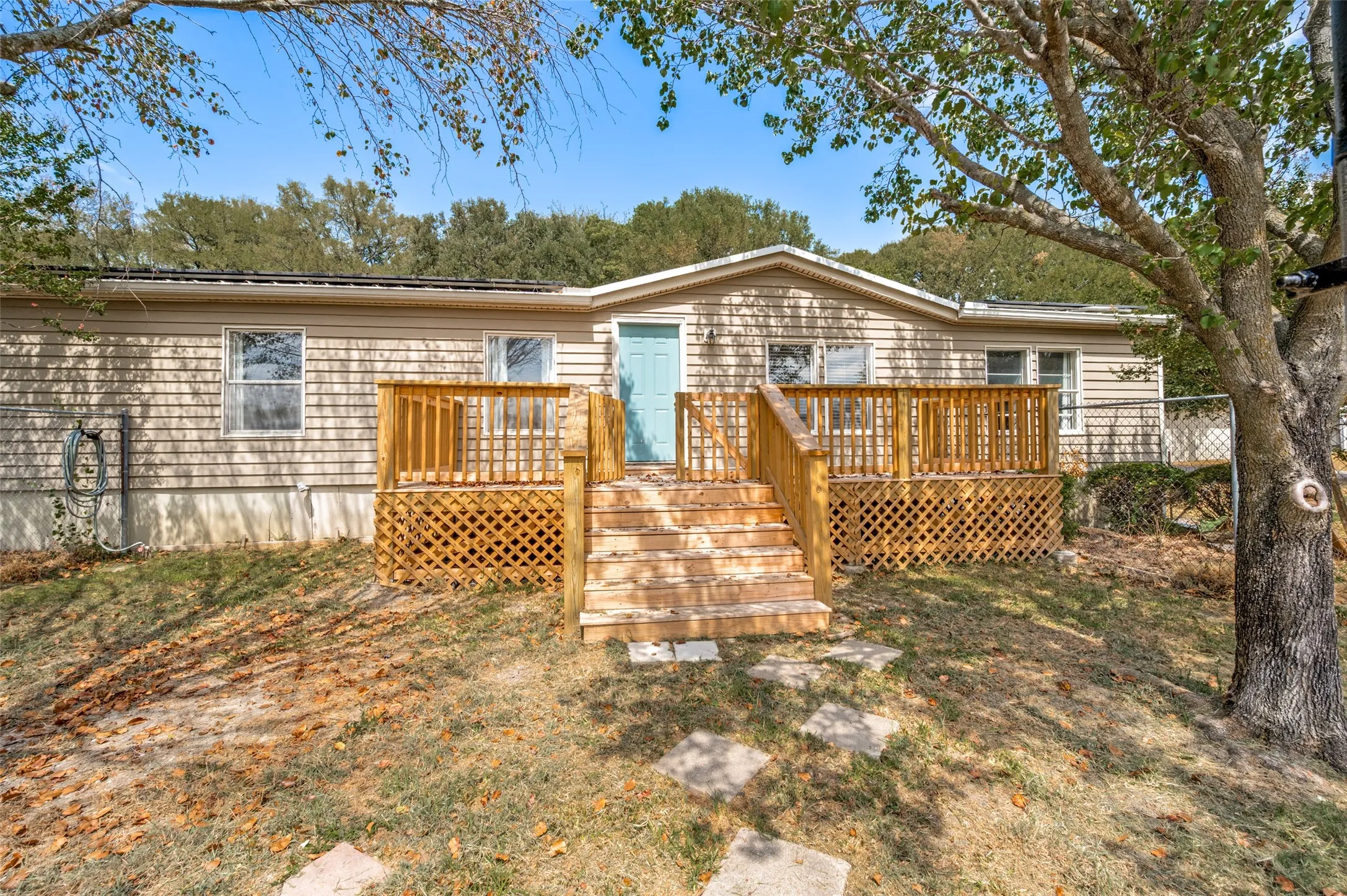 Front of home inside the fence with vinyl siding for easy maintenance and large wooden deck for entertaining.