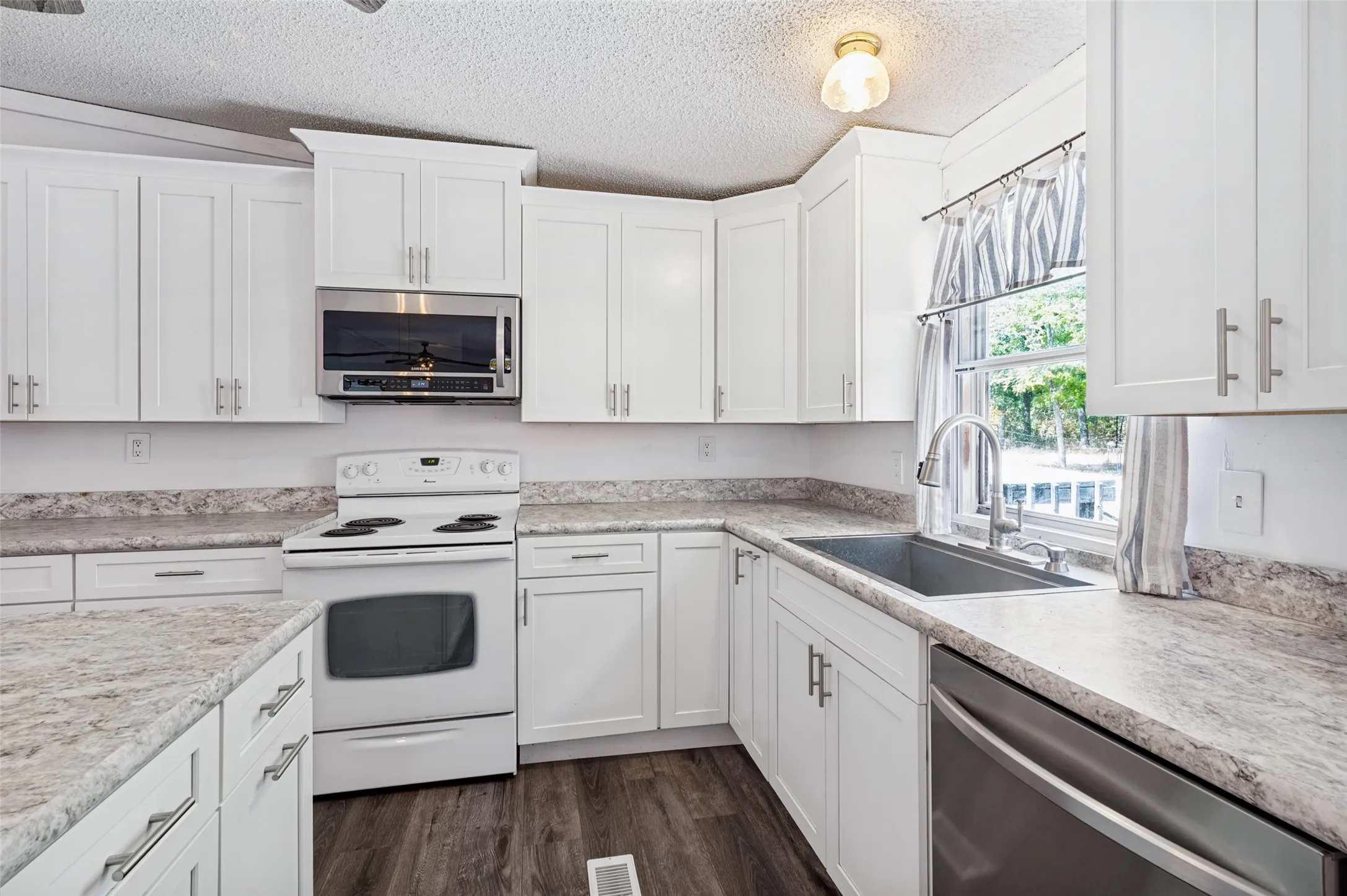 Kitchen with electric range and microwave above.