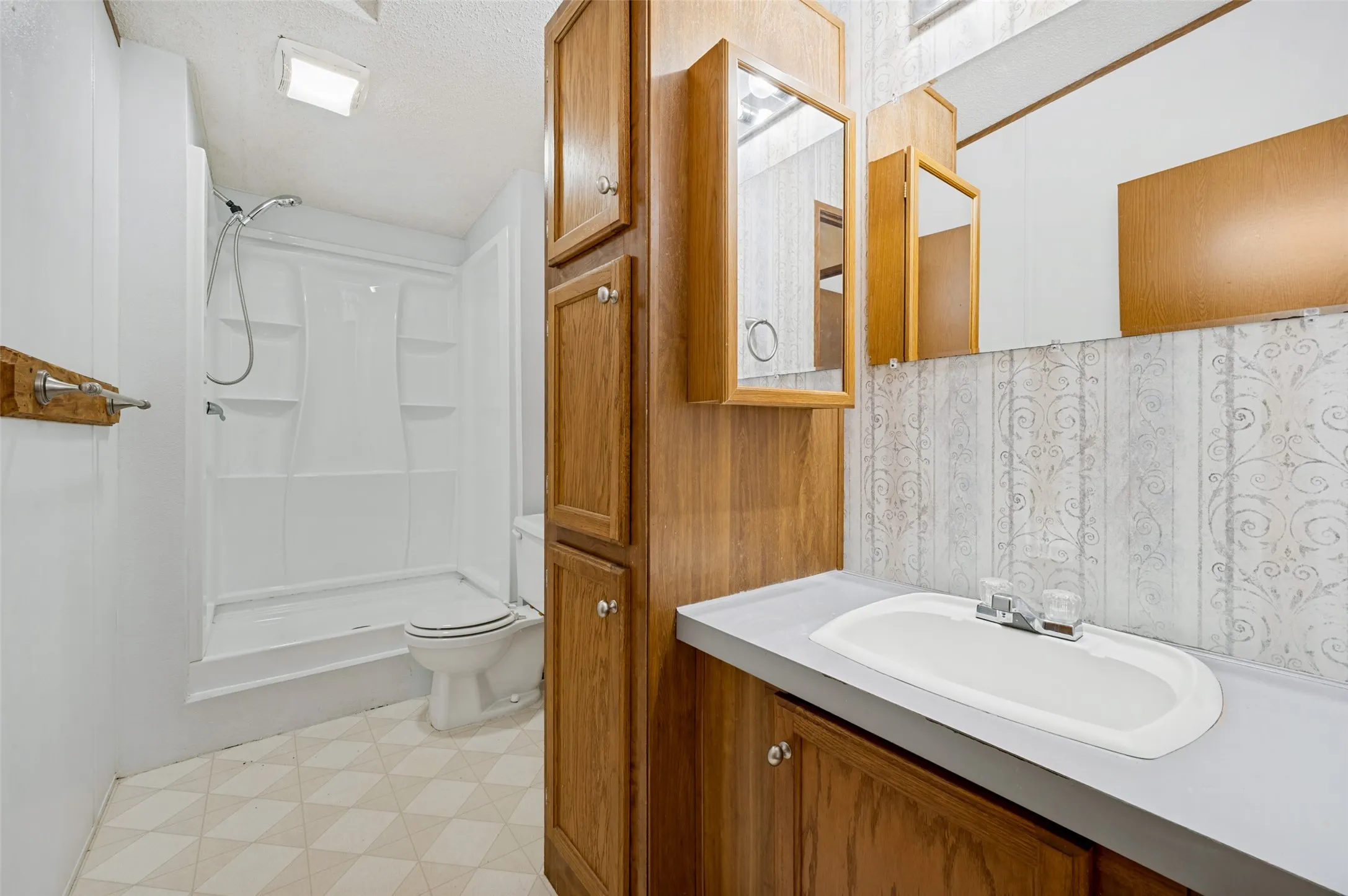 secondary bathroom with lots of cabinets for storage, a medicine cabinet and recently replaced walk-in shower.