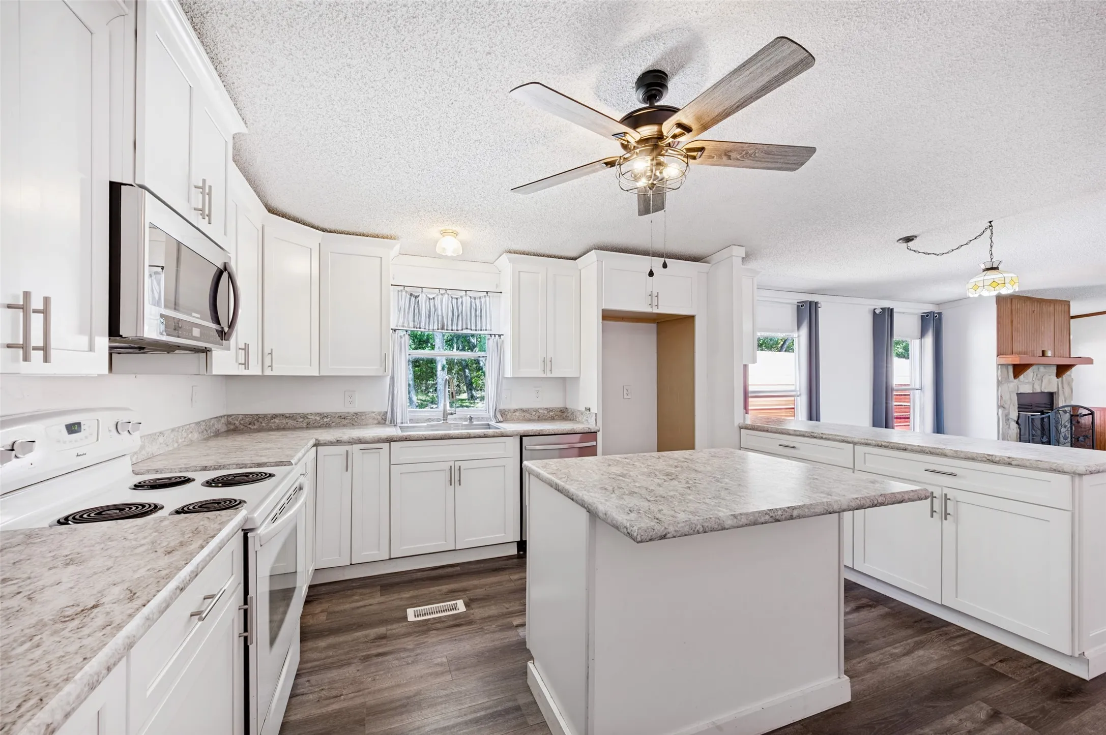 The kitchen includes an island with overhang for barstools, a nice window above the sink and plenty of cabinets.