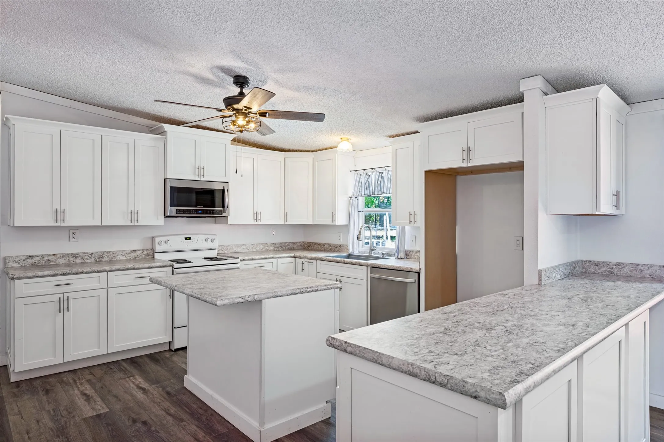 Nicely updated kitchen includes white, shaker style cabinets with brushed nickel cabinet pulls.