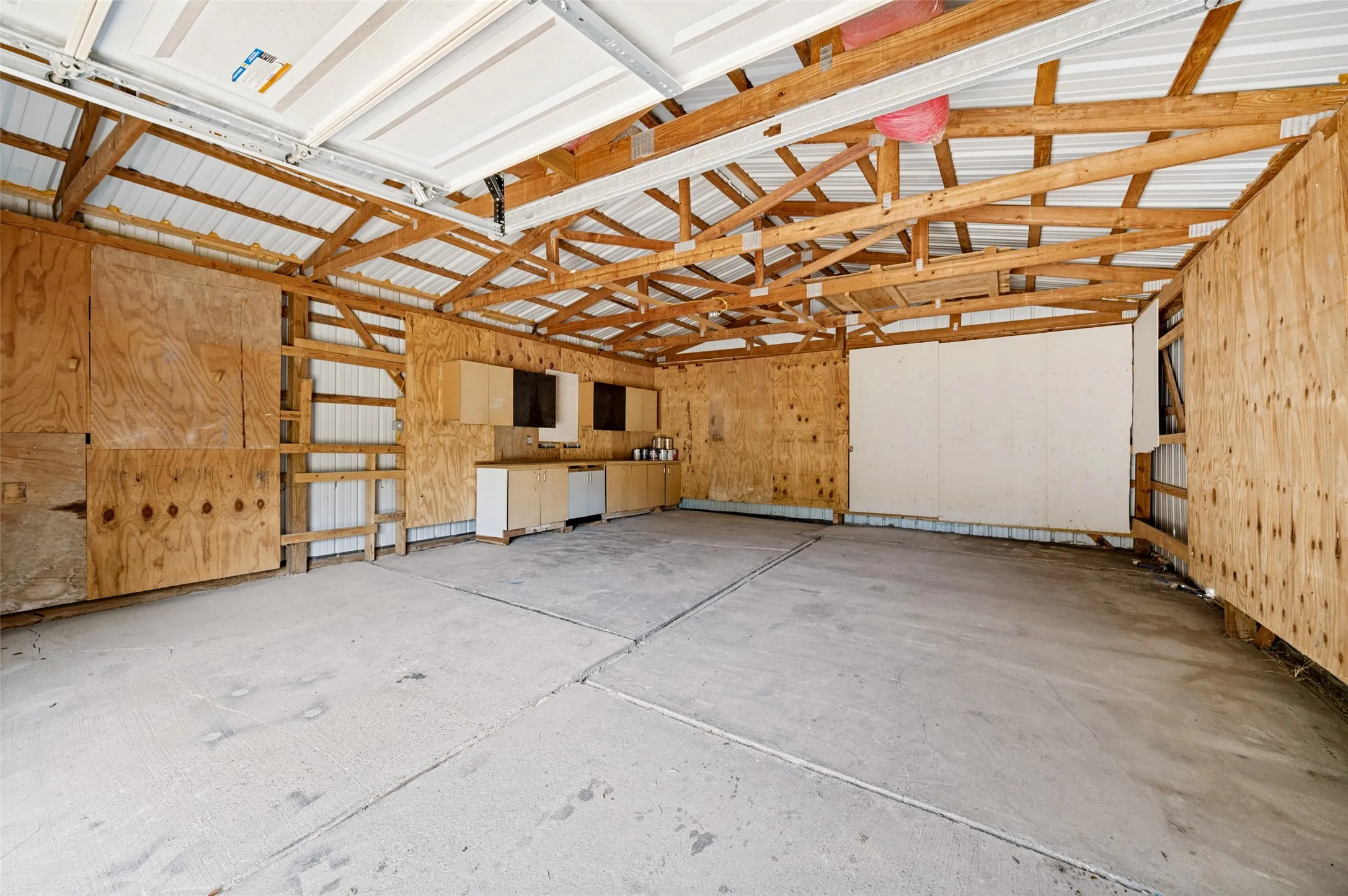 Large workshop with concrete floors, electricity and built in cabinets for storage.