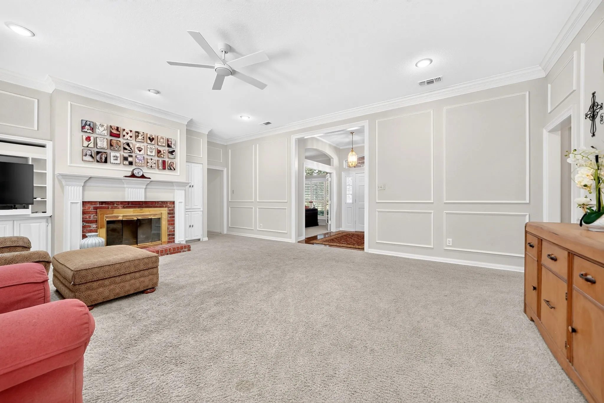 Recessed lighting, crown molding, fireplace with brick surround, built-in shelving, and decorative wall molding