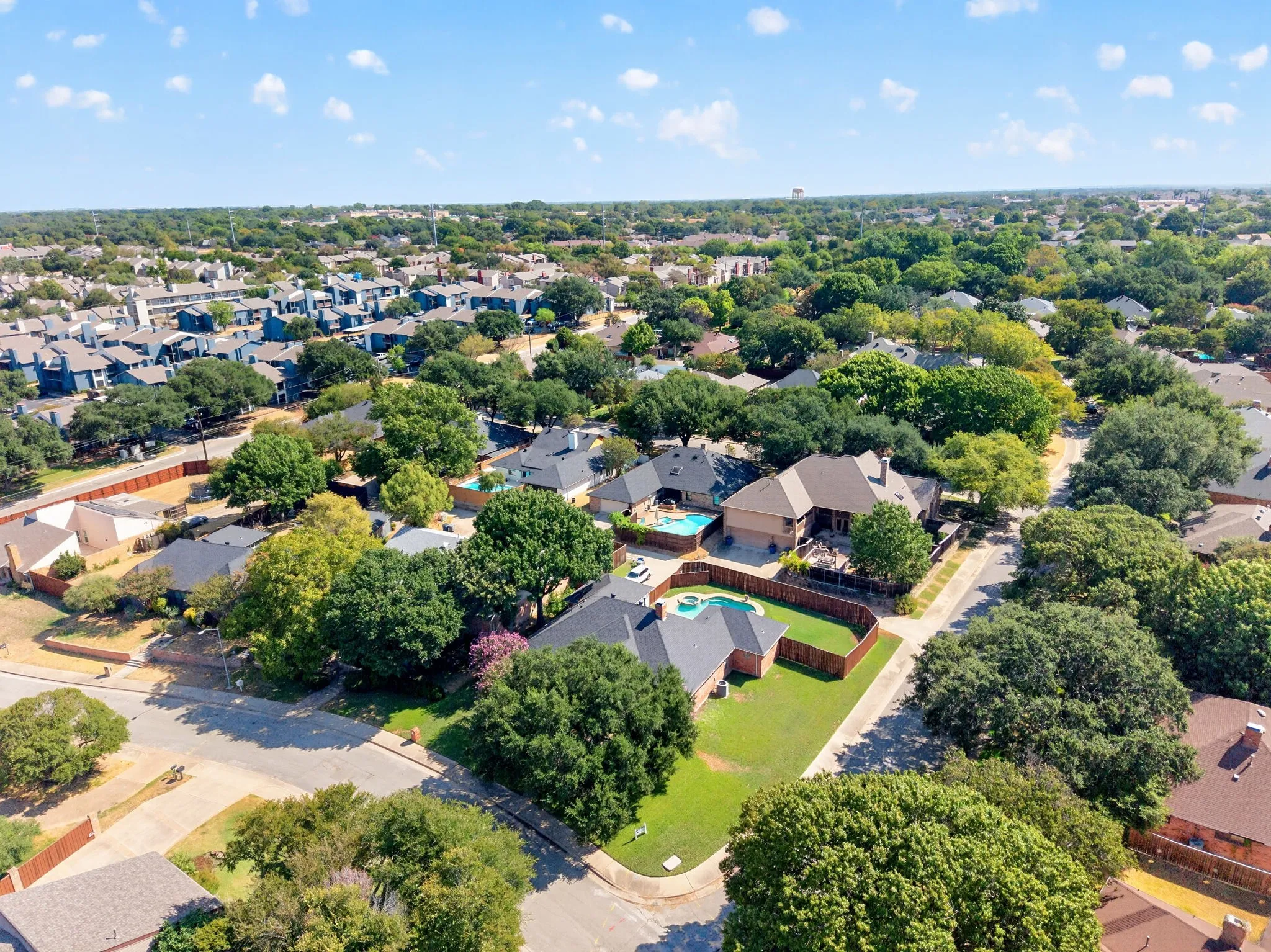 Aerial perspective showcasing residential properties with private swimming pools, mature trees, and fenced yards