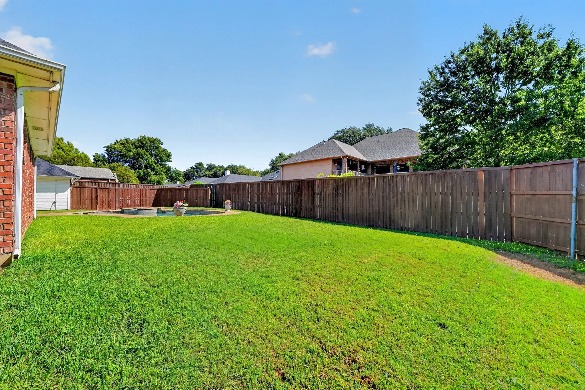 Expansive backyard featuring a manicured lawn, wood privacy fencing, and an in-ground swimming pool