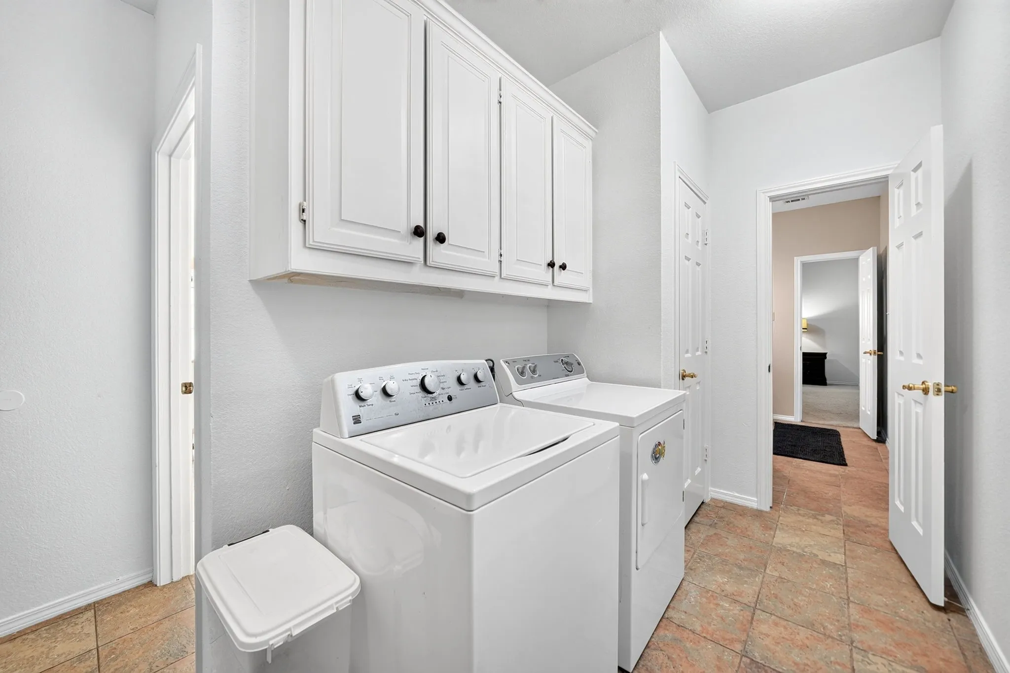 Laundry area with white cabinetry, tile flooring, and white paneled doors
