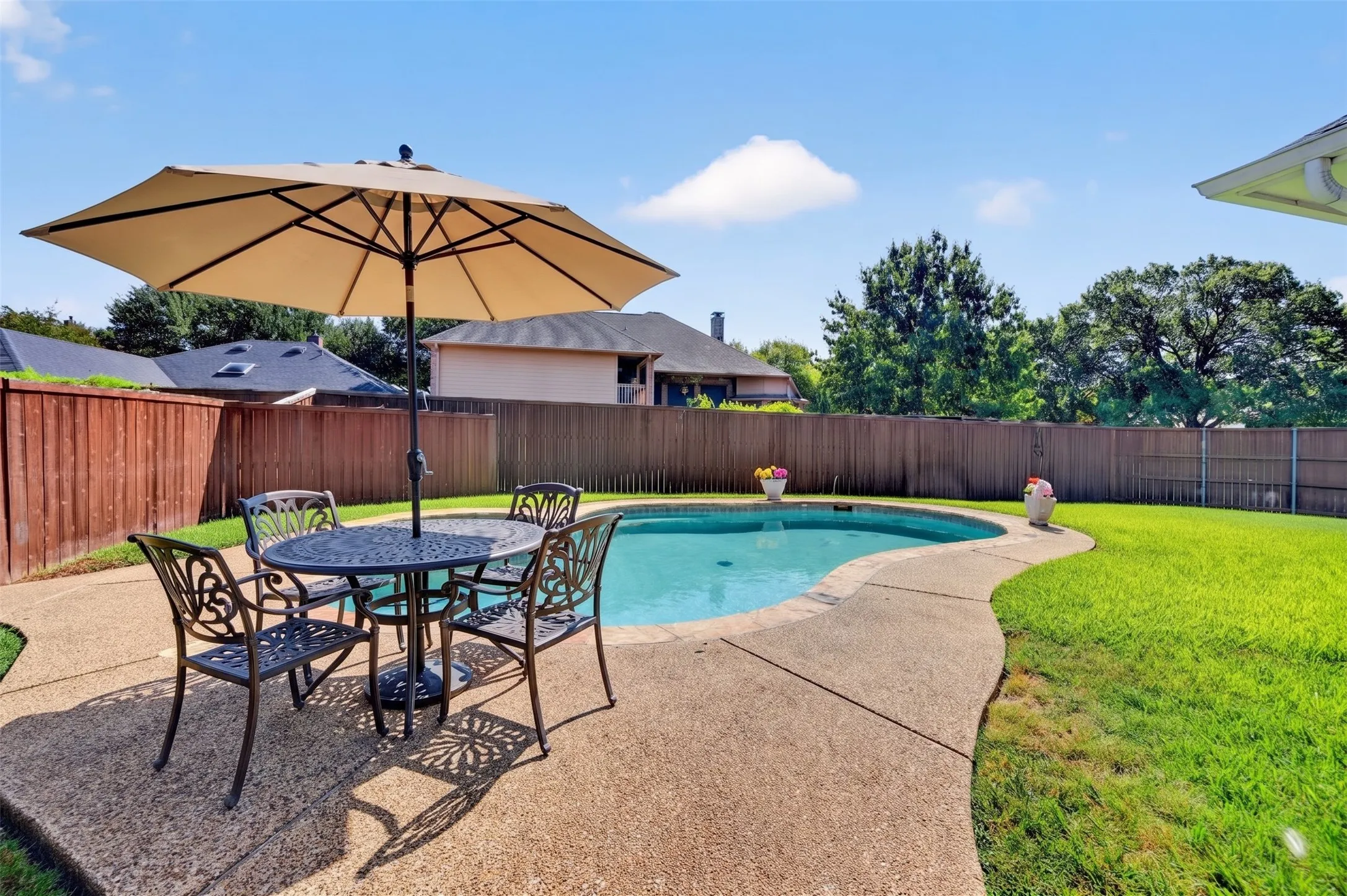 Curved in-ground swimming pool with stone coping and surrounding concrete patio