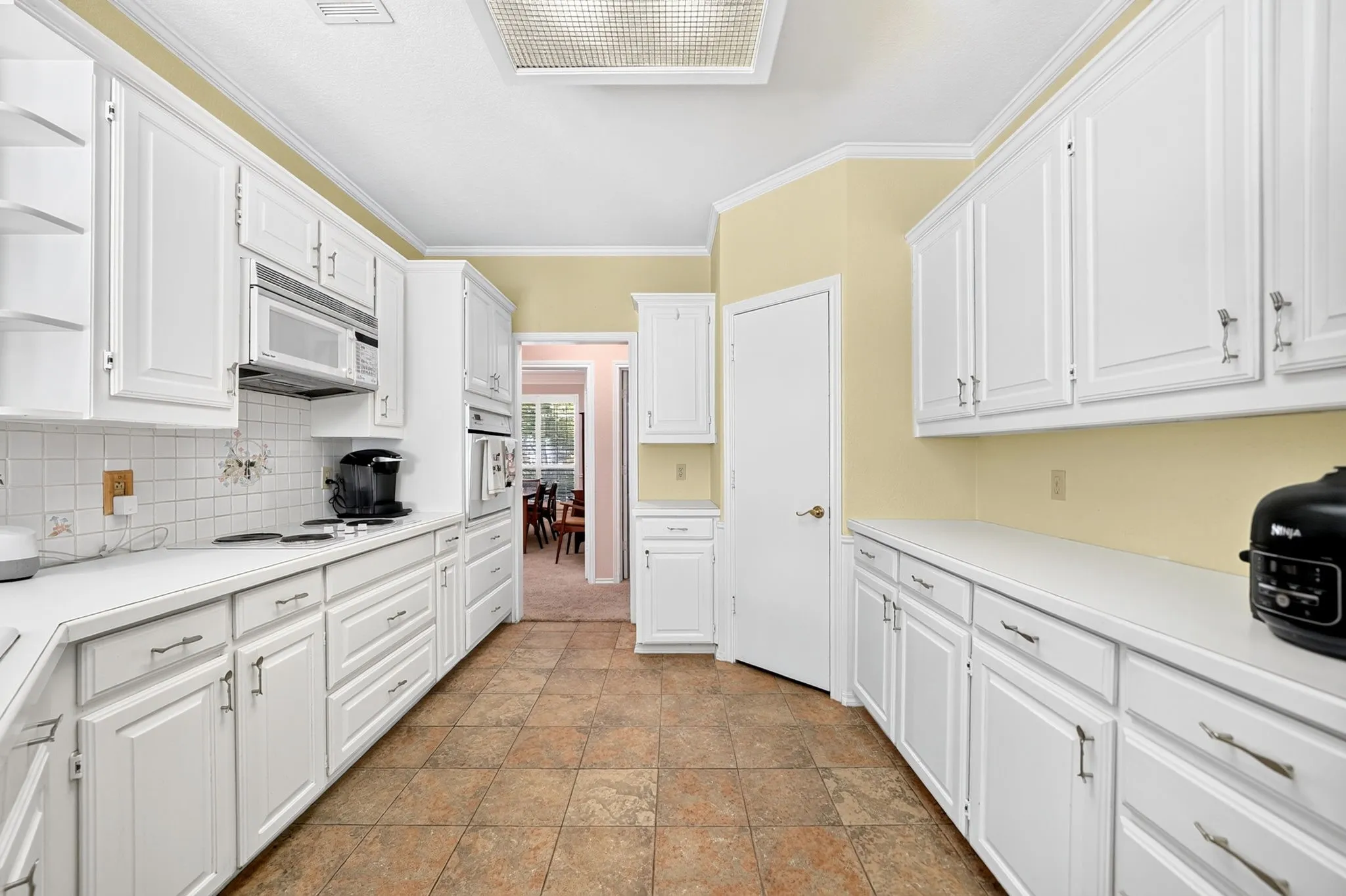 White cabinetry with brushed nickel hardware, light-toned countertops, and tile flooring