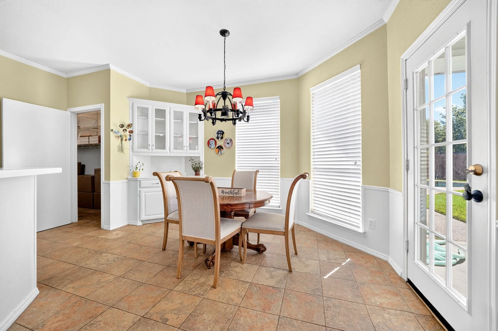 Tile flooring, built-in cabinetry, French door, two large windows, and a decorative chandelier