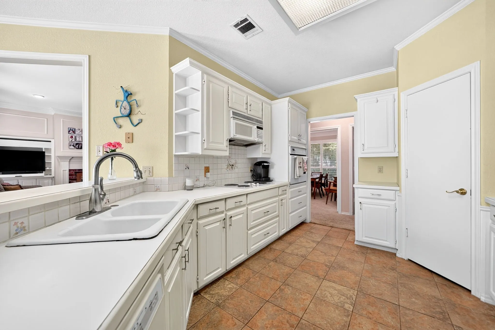 Kitchen featuring white cabinetry, tile countertops, a double basin sink with a gooseneck faucet, integrated wall oven, and tile flooring