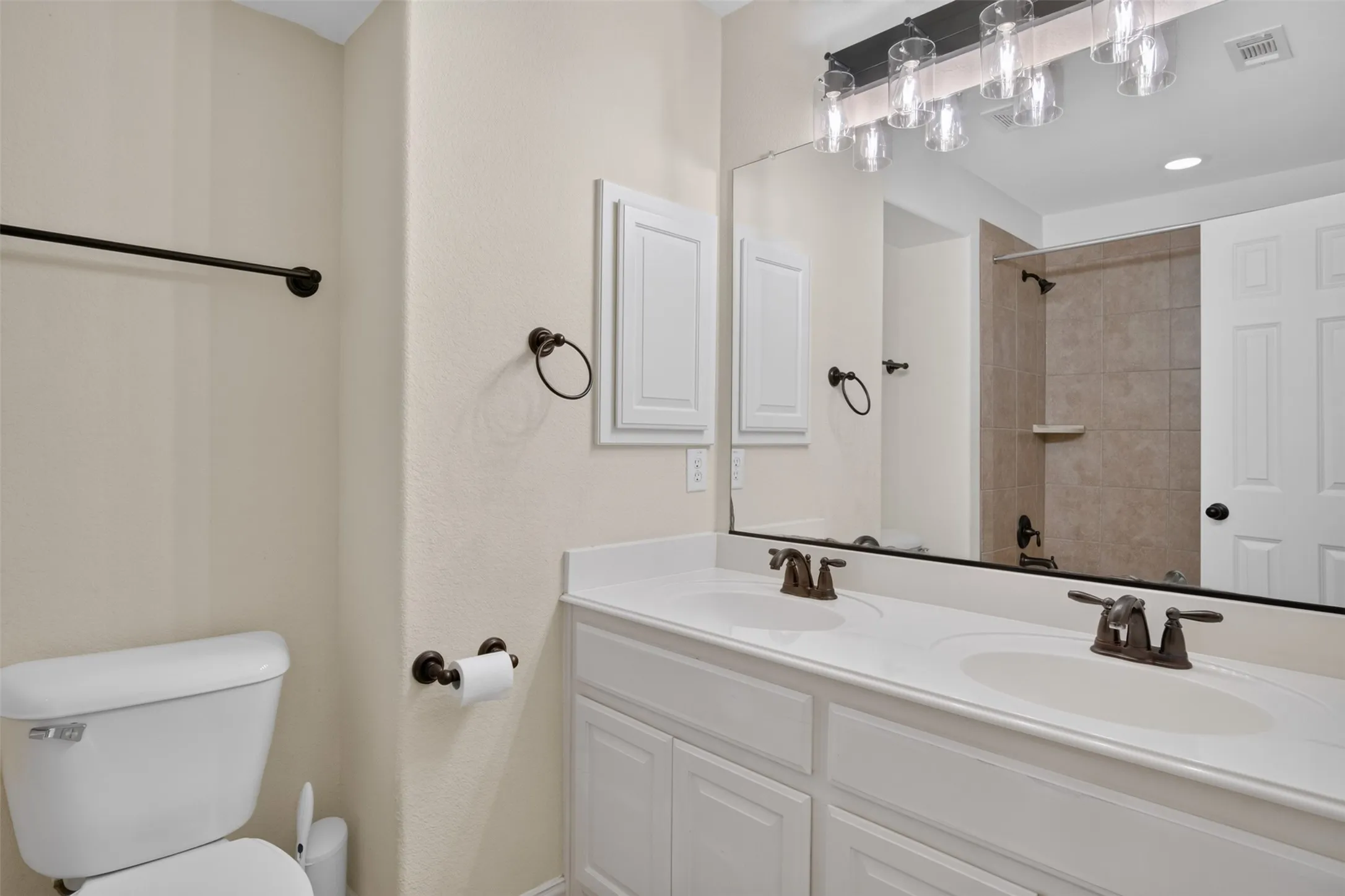 Dual-vanity bathroom featuring a white cabinetry base with ample storage, wide quartz countertop, and large framed mirror with matte black hardware