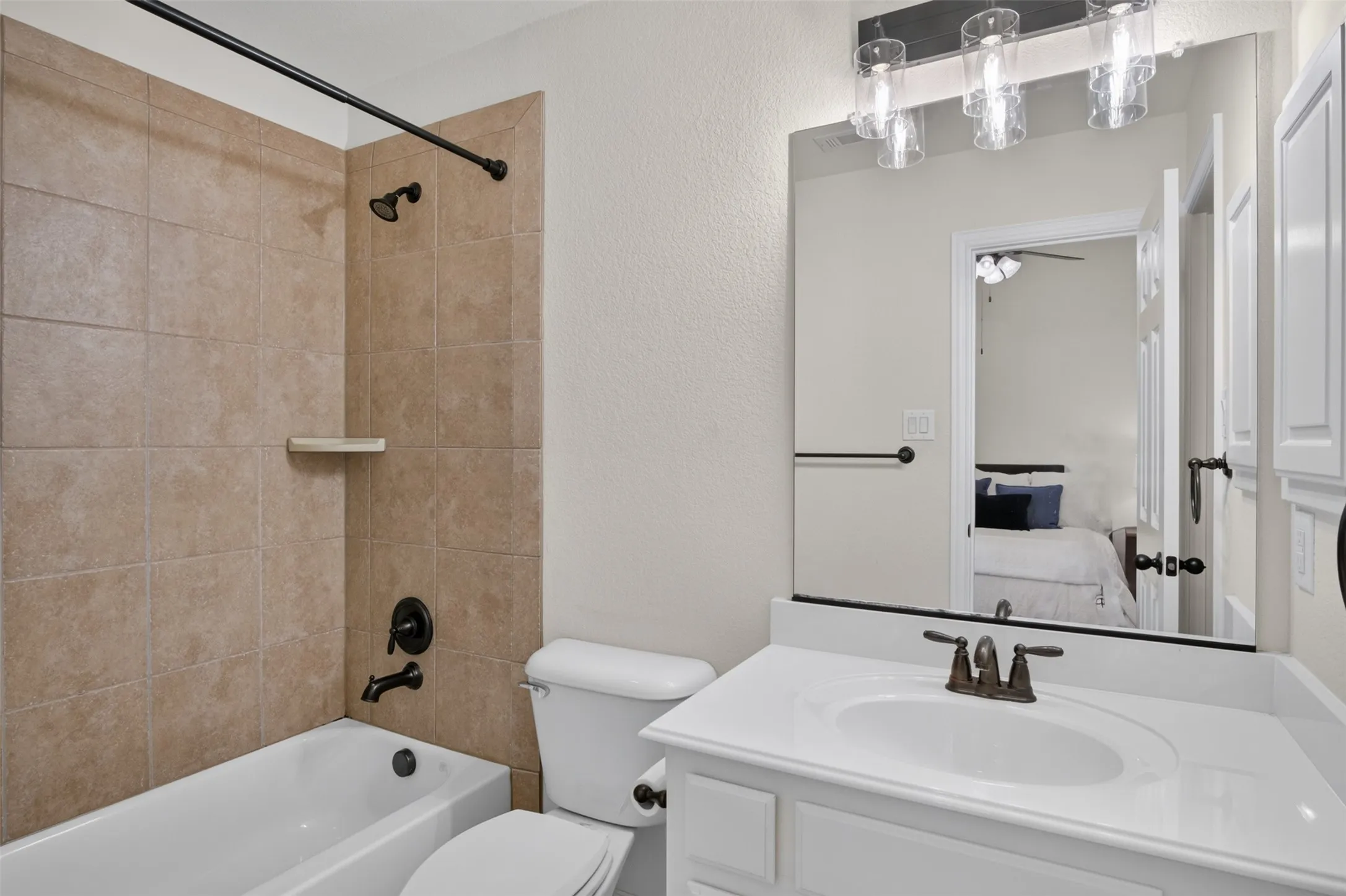 Bathroom featuring a tub/shower combination with tile surround, a single vanity with a white countertop, and white cabinetry