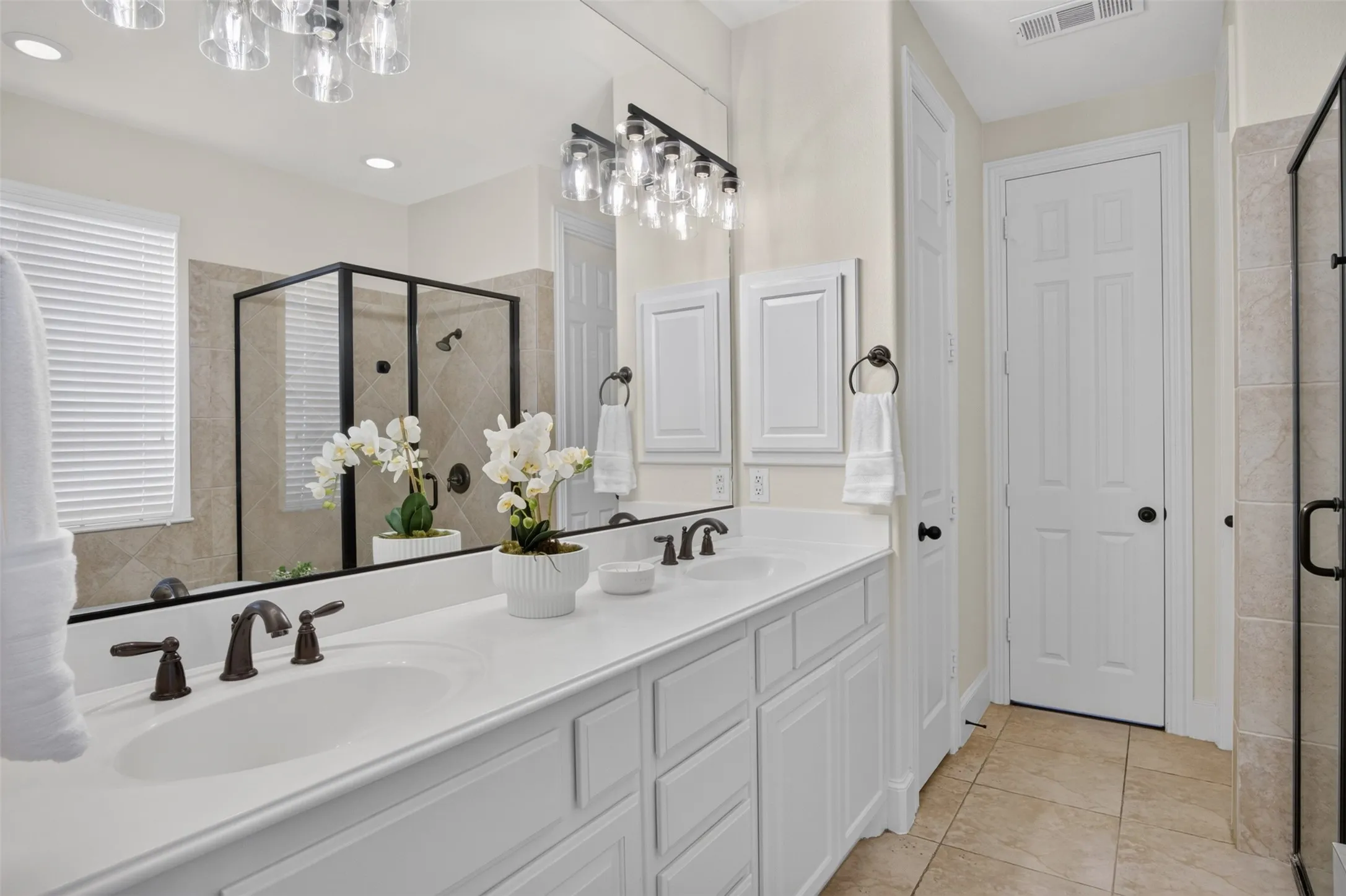 Dual vanity with white cabinetry, bronze fixtures, and a large mirror