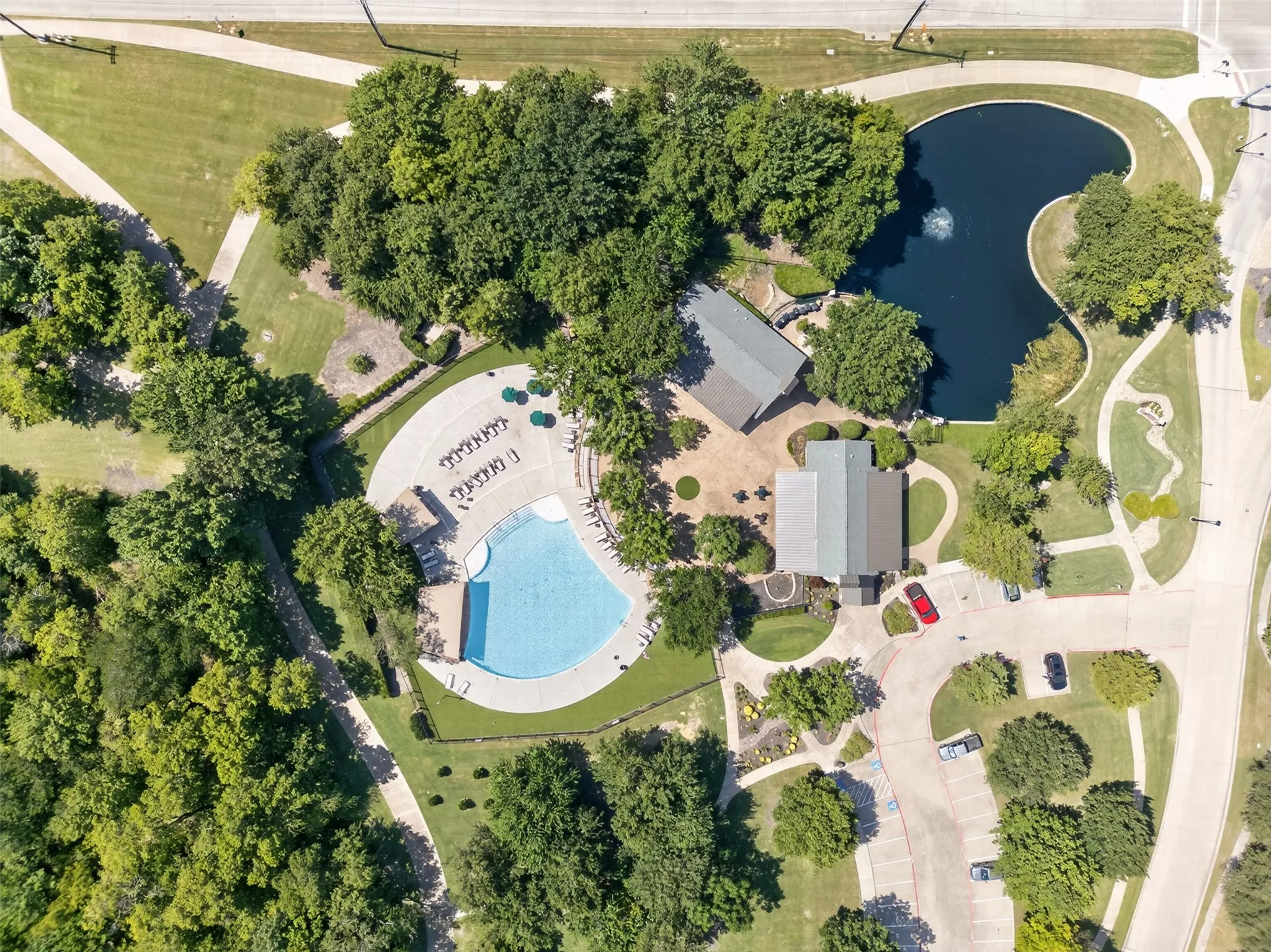 Expansive community amenities including a swimming pool, shaded pool deck, two community buildings, a pond feature, and paved walkways