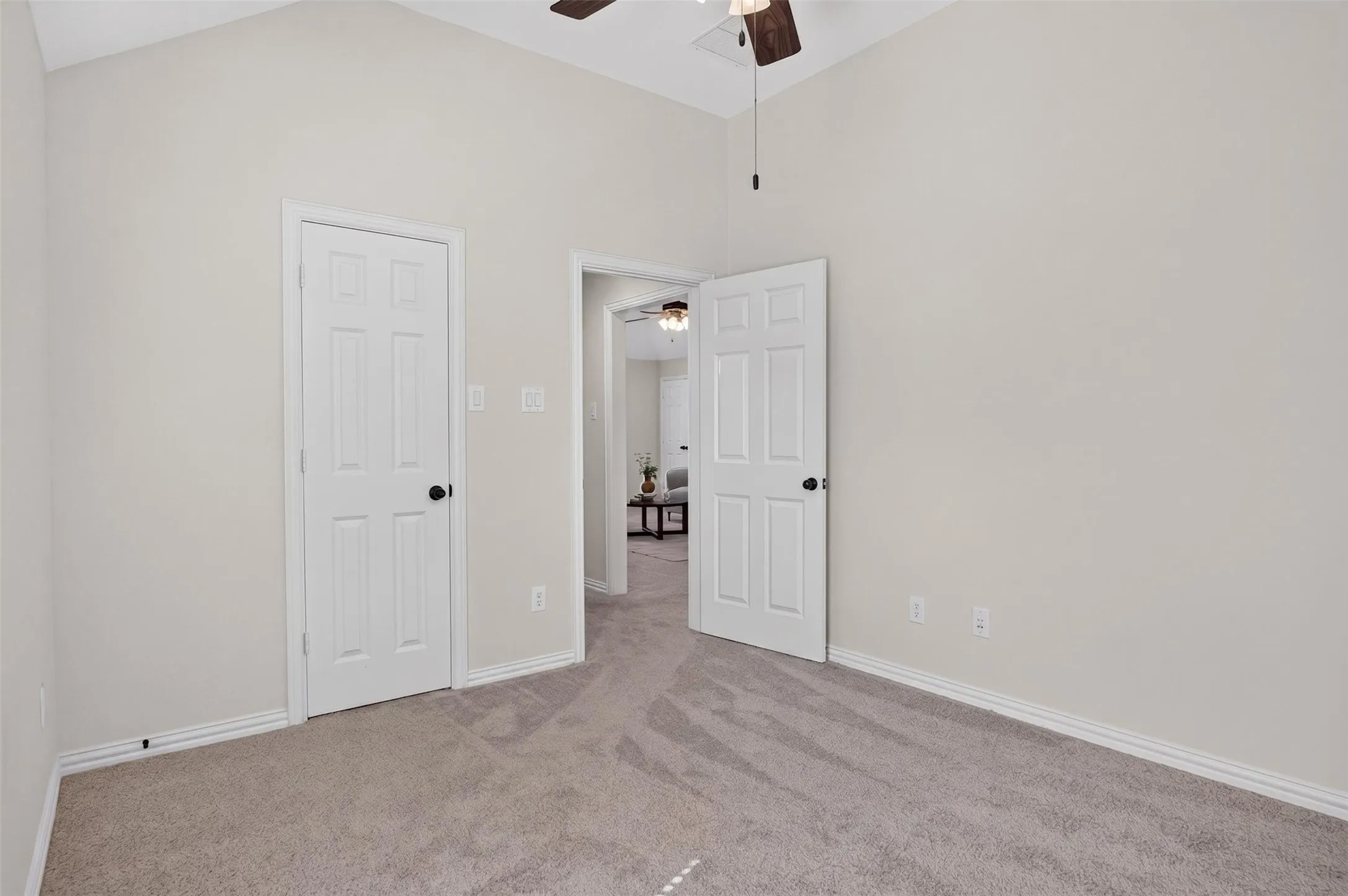 Vaulted ceiling with a ceiling fan, light-toned wall paint, and gray carpet flooring