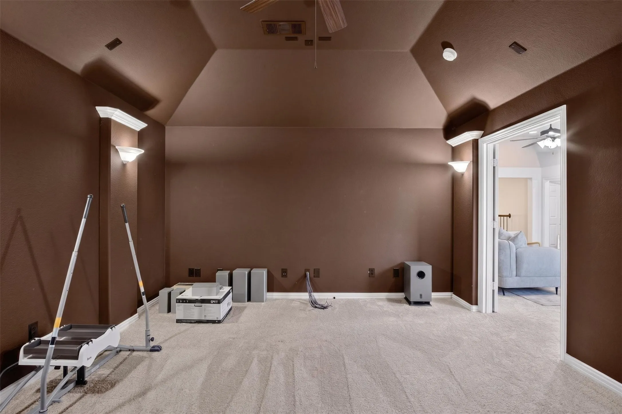 Vaulted ceiling with a ceiling fan, wall sconces, and recessed lighting