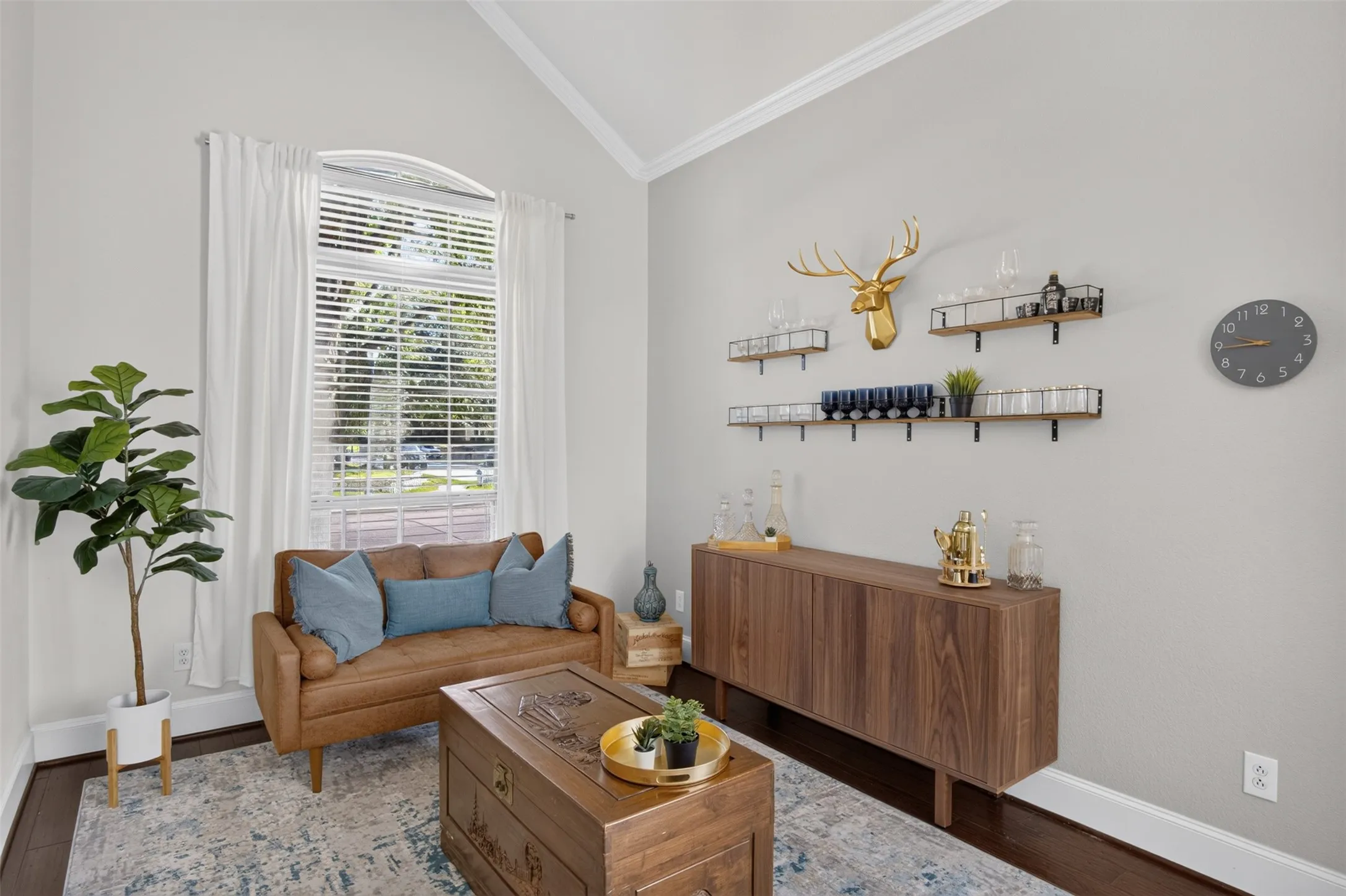 Vaulted ceiling with crown molding, arched transom window, wood-finish flooring, and built-in wall shelving