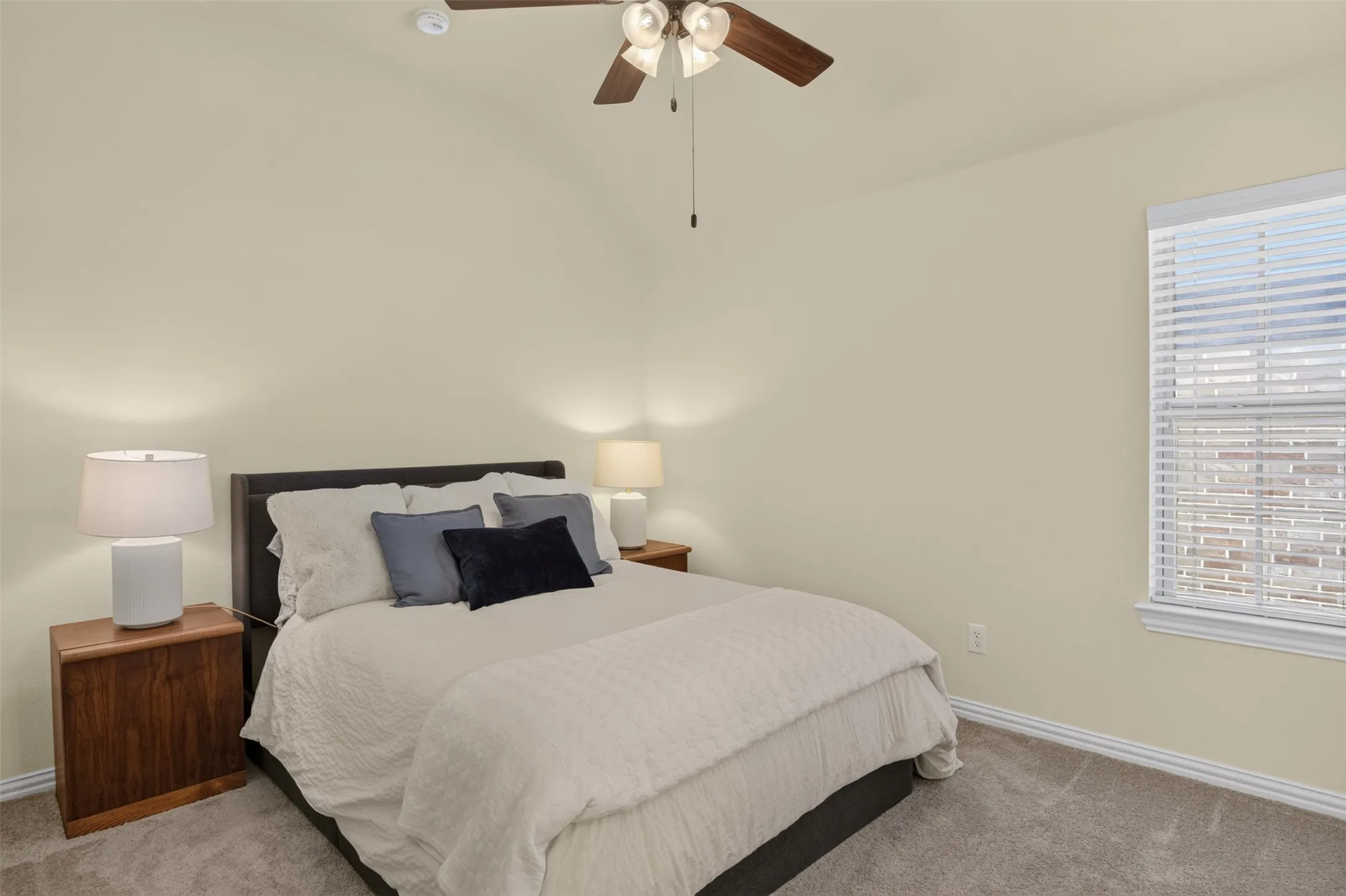 Vaulted ceiling with a ceiling fan, window with blinds, and neutral carpeting