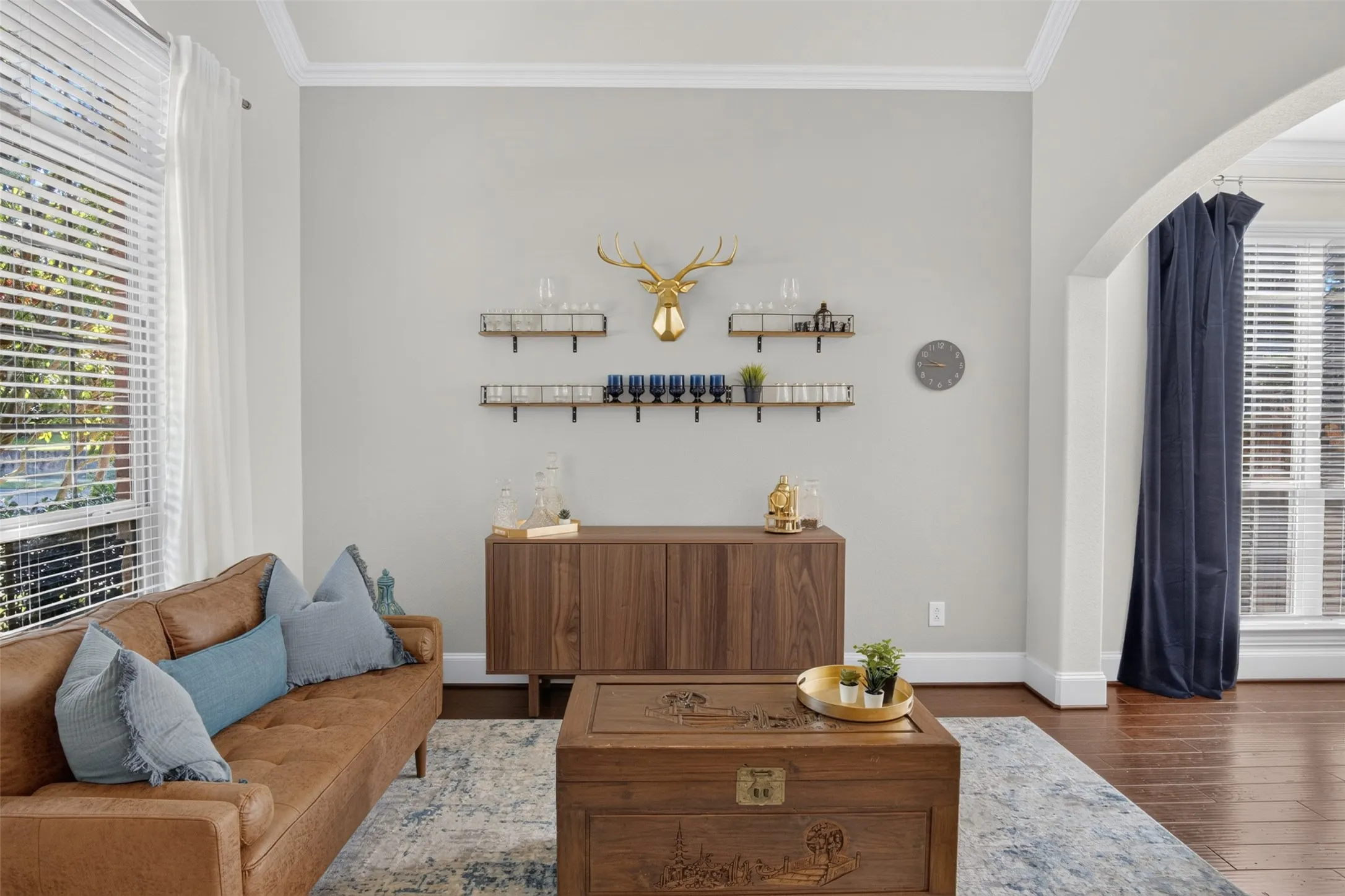 Crown molding, wood-finish flooring, arched doorway, window with blinds, light gray wall color