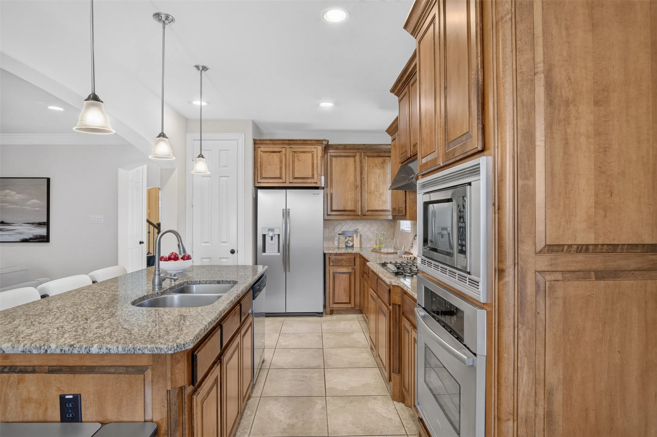 Kitchen featuring wood cabinetry, granite countertops, stainless steel appliances, a double basin sink, and tile flooring