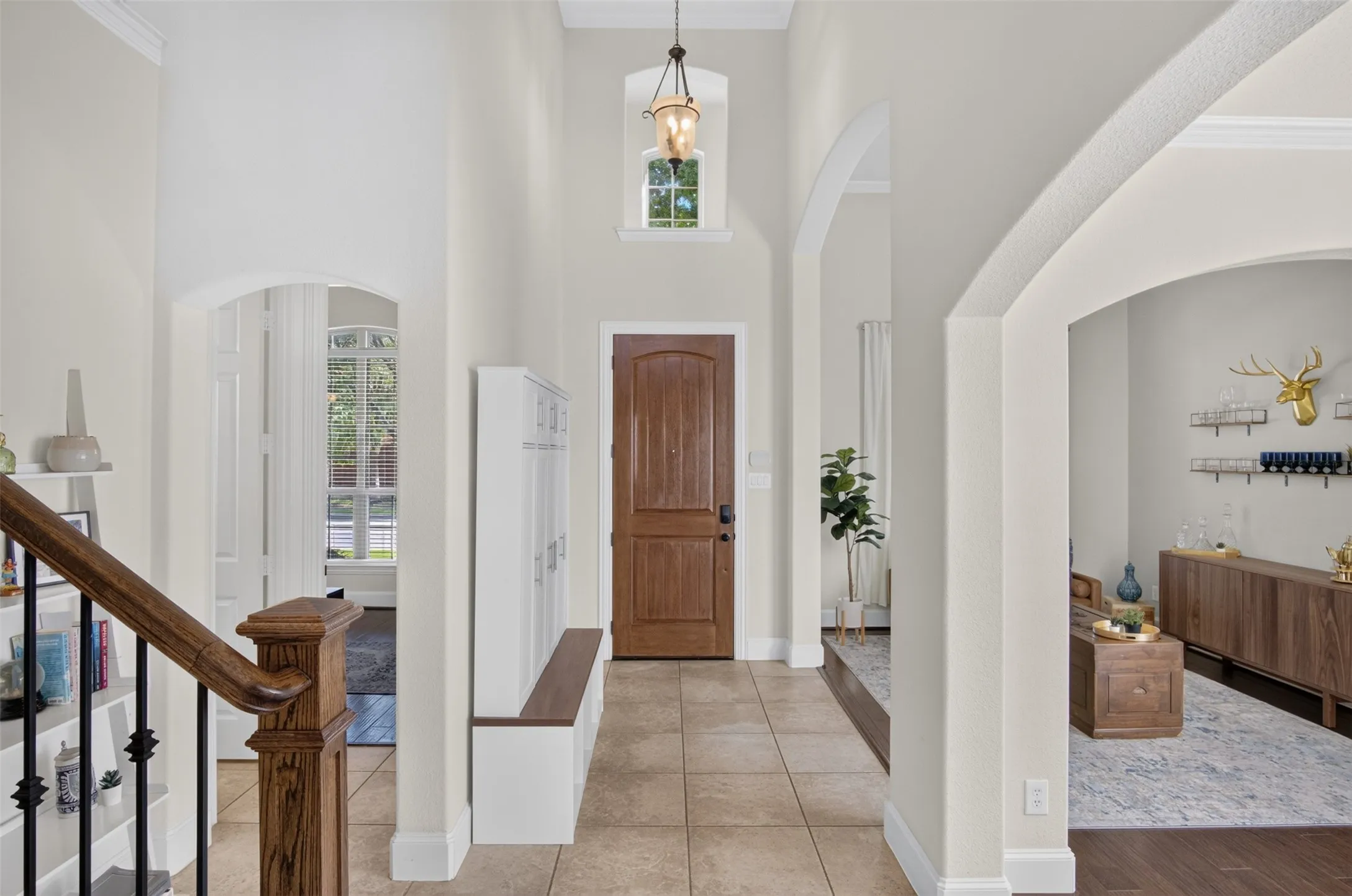 Two-story foyer with tile flooring, a wood front door, and an arched entryway