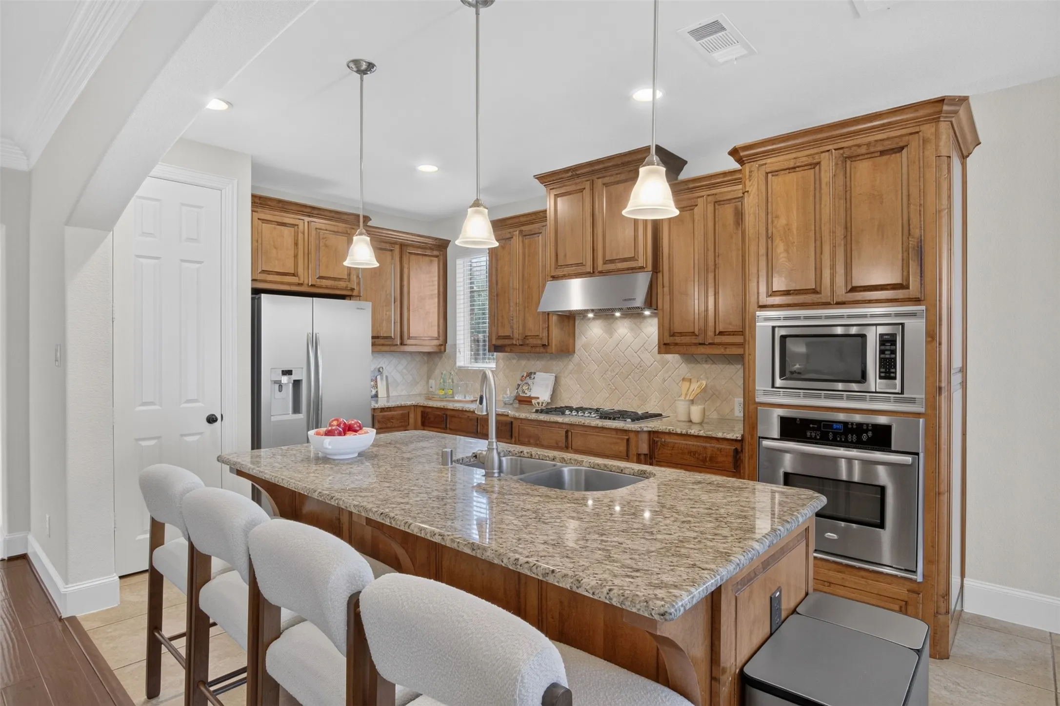 Kitchen featuring a central island with an undermount sink, granite countertops, wood cabinetry, stainless steel appliances, and recessed lighting
