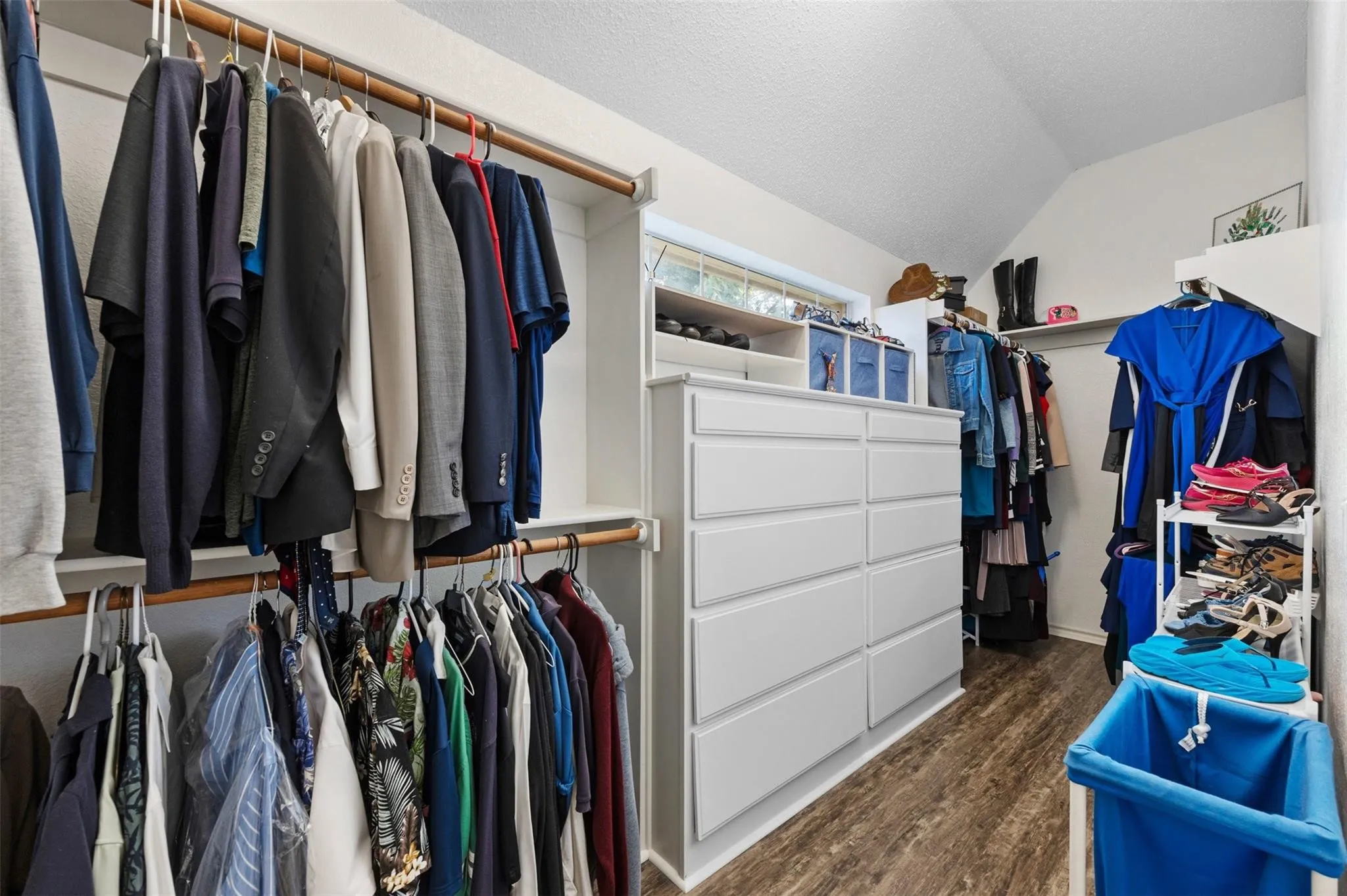 Walk-in closet featuring wood-finish flooring, built-in shelving, and a multi-drawer dresser