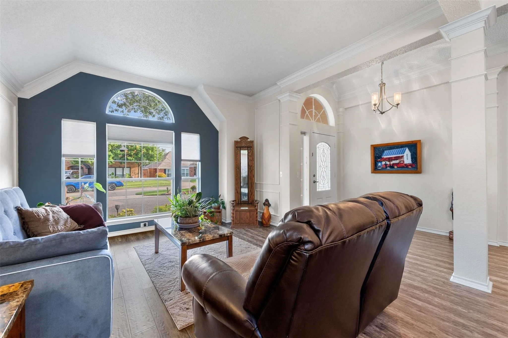 Vaulted ceilings, wood-finish flooring, decorative entryway with arched transom, and a large picture window with an arched transom