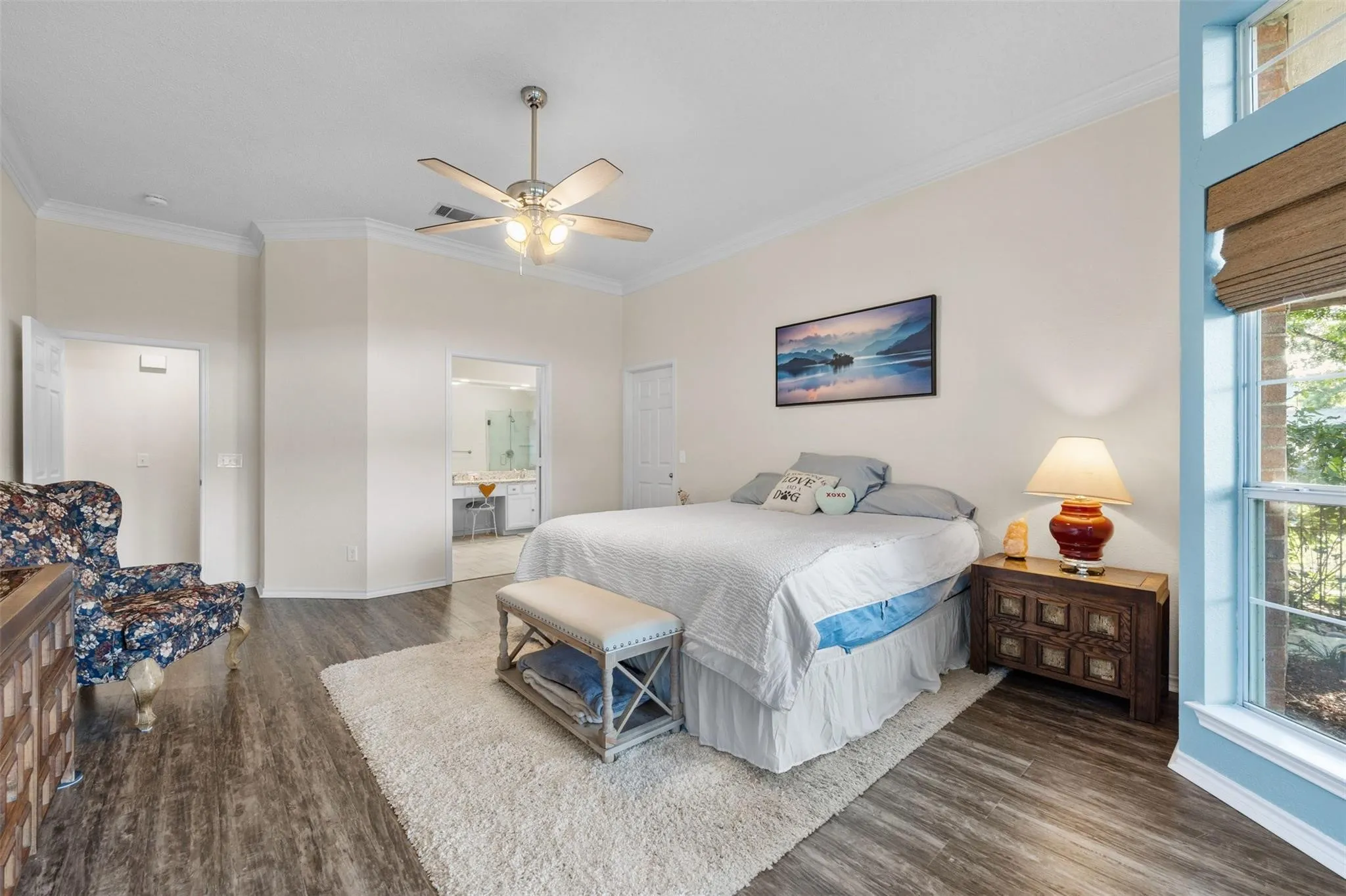 Wood-finish flooring, ceiling fan with integrated lighting, crown molding, and large window with natural light