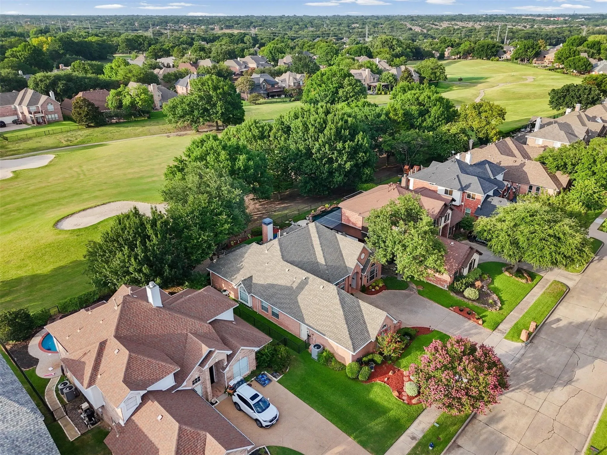 Aerial perspective showcasing a residential neighborhood with a golf course backdrop